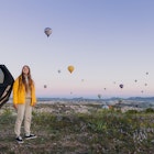Young female with long hair in warm jacket enjoying the road trip by a car, looking at the beautiful dawn above the picturesque valley with hundreds of hot air balloons in Turkey
1404229693