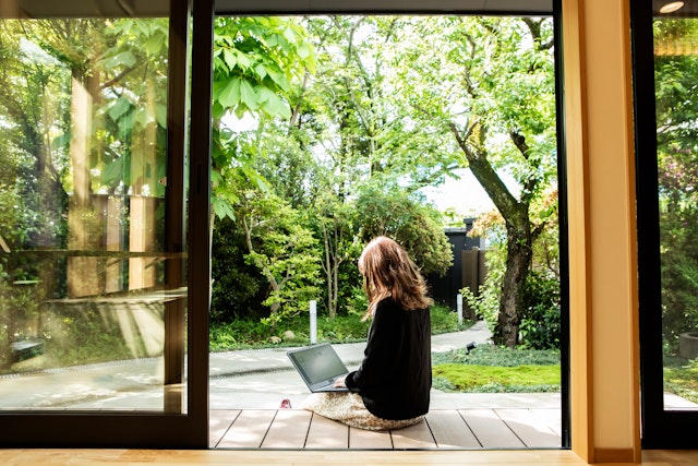 A woman working on her laptop outside a guesthouse in Japan