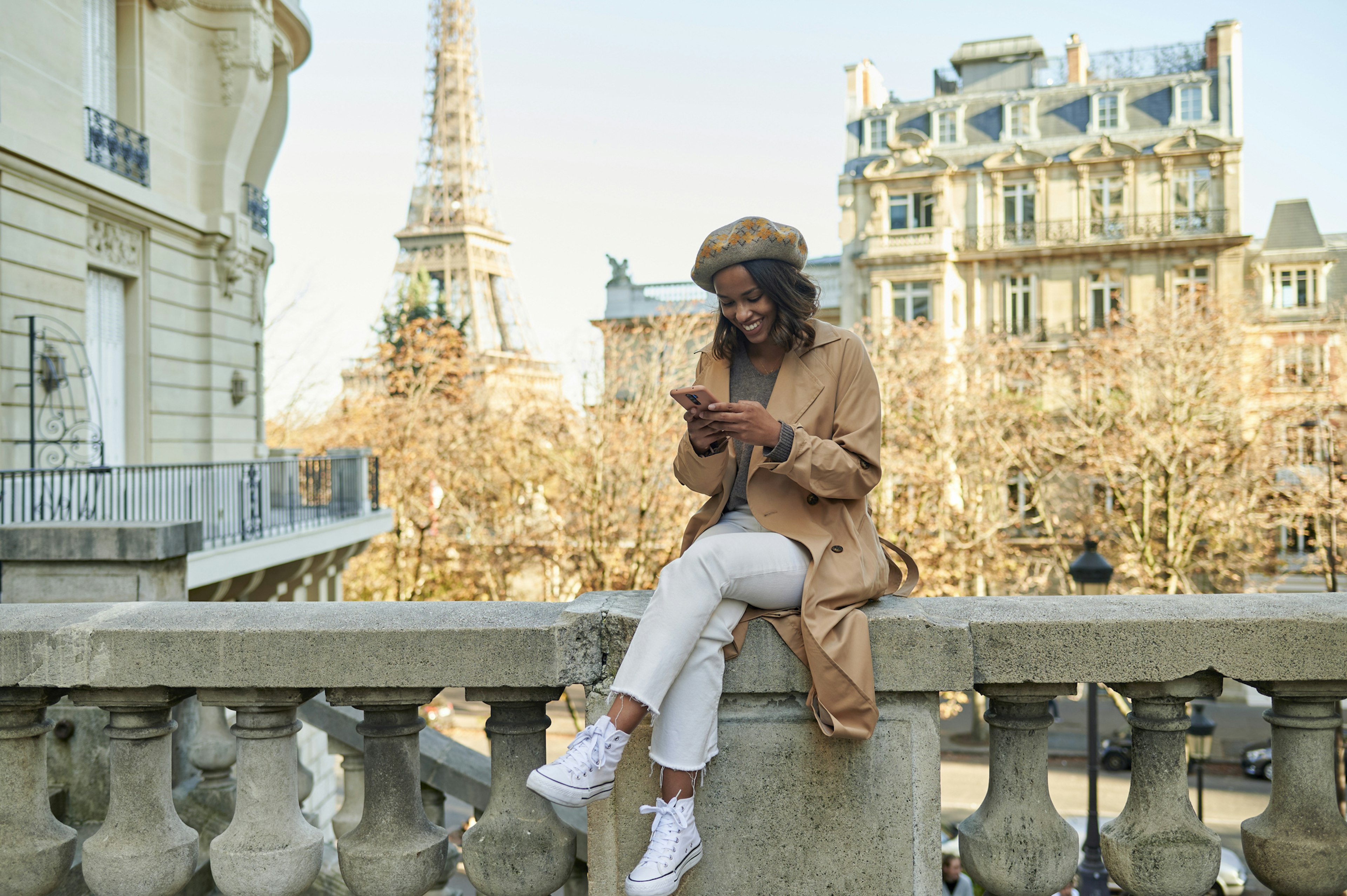 A woman using a mobile phone on a street in Paris with the Eiffel Tower in the background