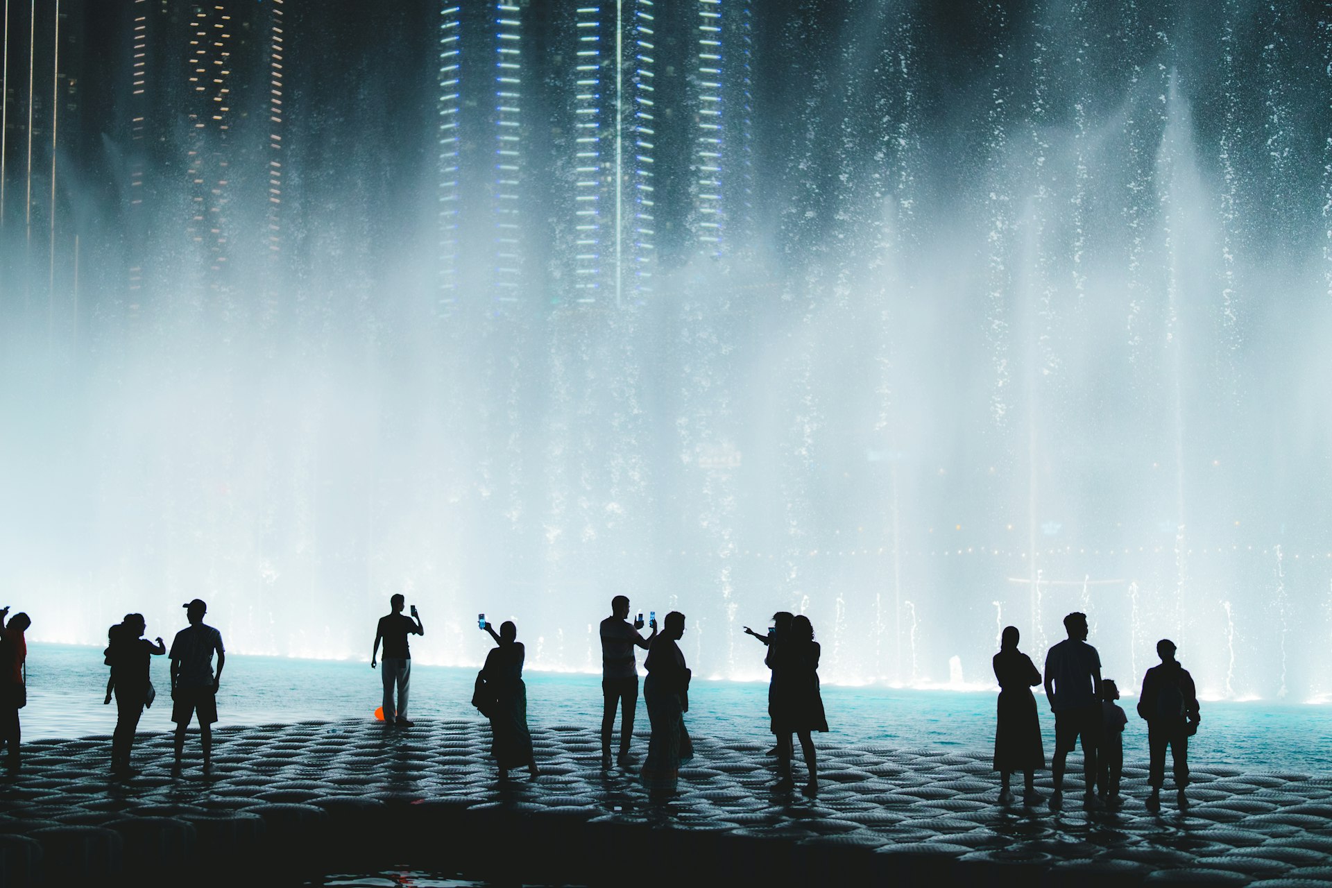 People stand close to the fountains in Las Vegas, backlit by the show lights