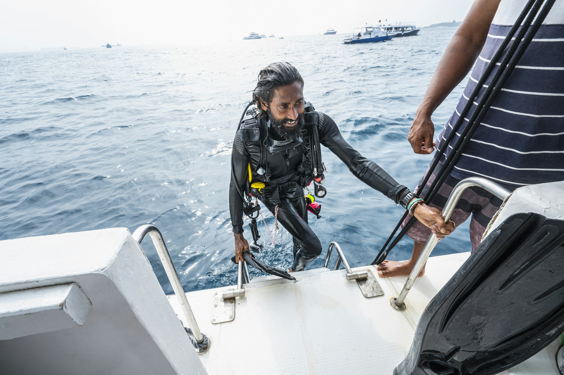 A diver clambers back into a boat after a dive in the ocean