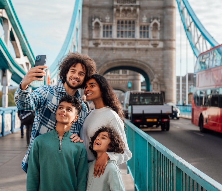 Multiracial family stand together on a bridge taking a selfie.
1680154341