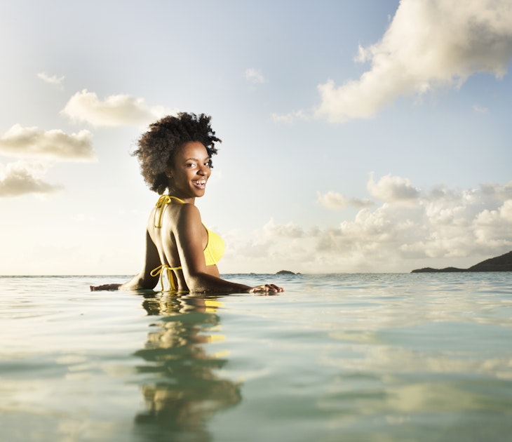 A smiling woman looking over her shoulder in the sea in Antigua