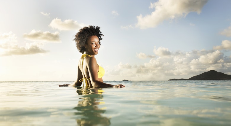 A smiling woman looking over her shoulder in the sea in Antigua