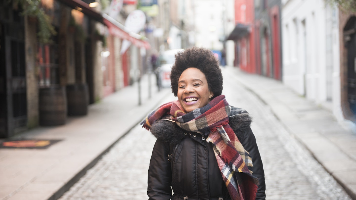 A young woman smiling as she walks through Temple Bar in Dublin