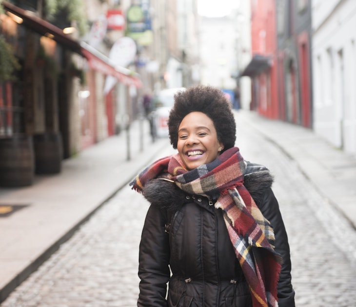 A young woman smiling as she walks through Temple Bar in Dublin