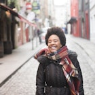 A young woman smiling as she walks through Temple Bar in Dublin