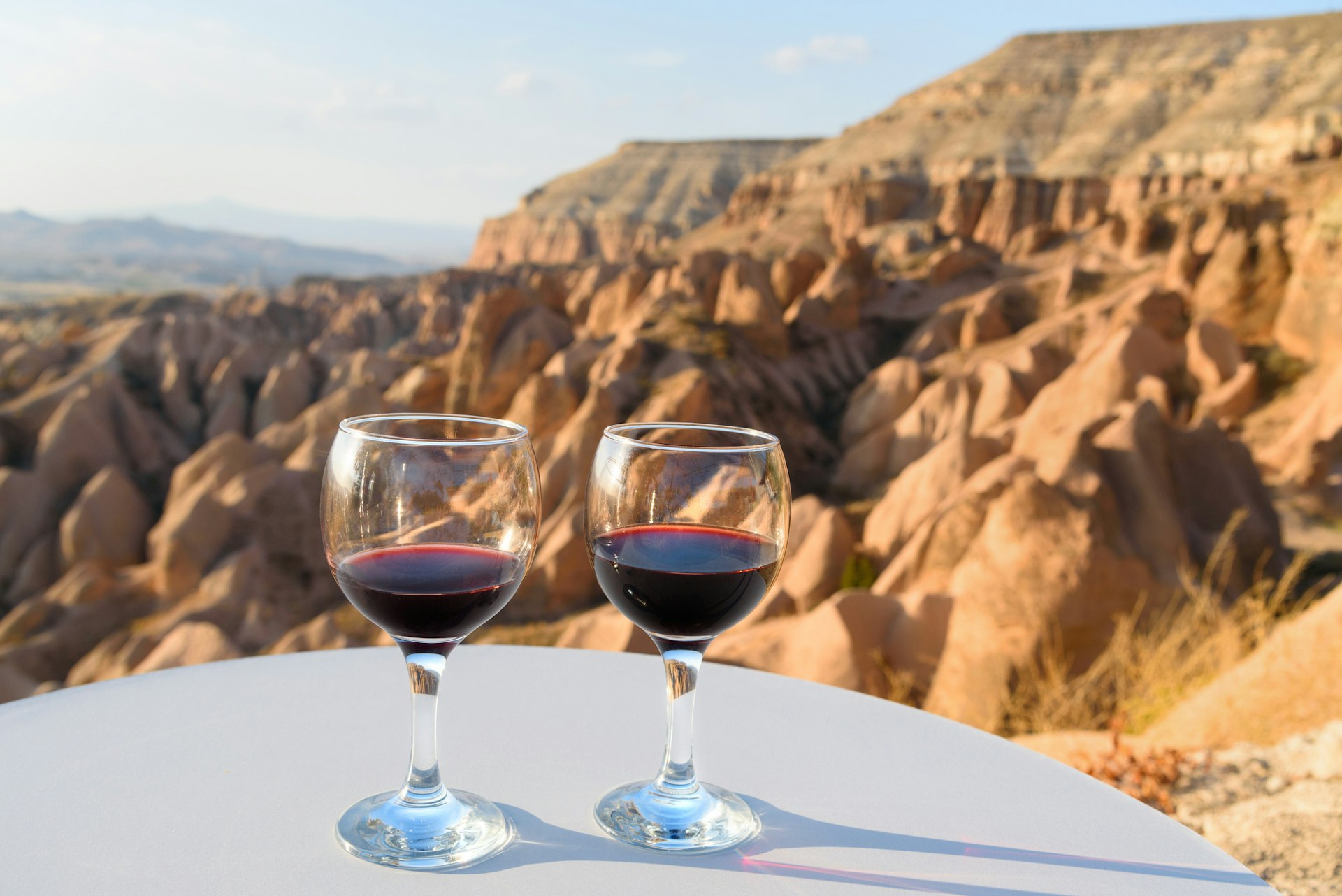 Two glasses of red wine set against a rugged desert valley