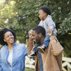 A Black family laughing together in a park