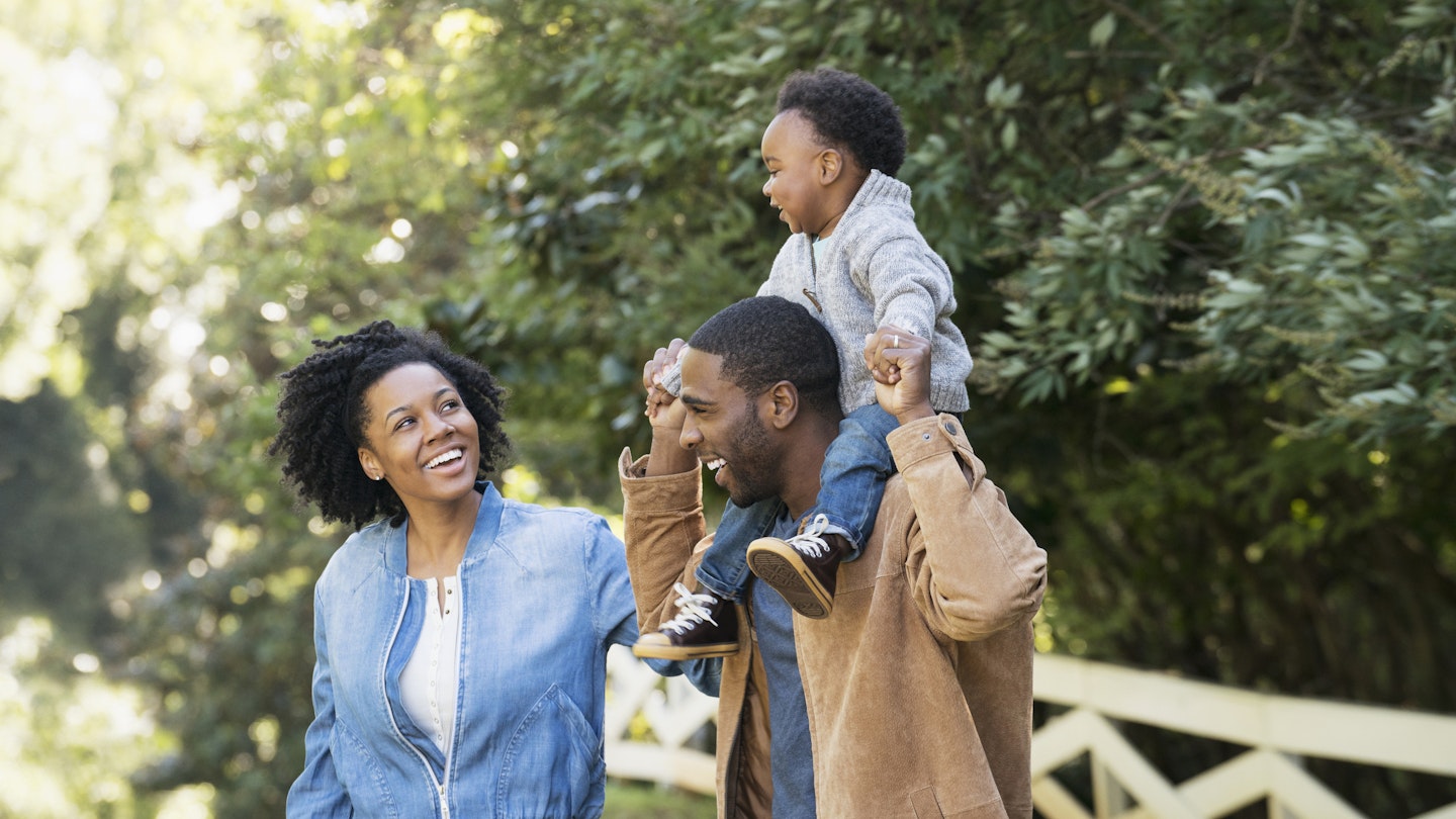 A Black family laughing together in a park