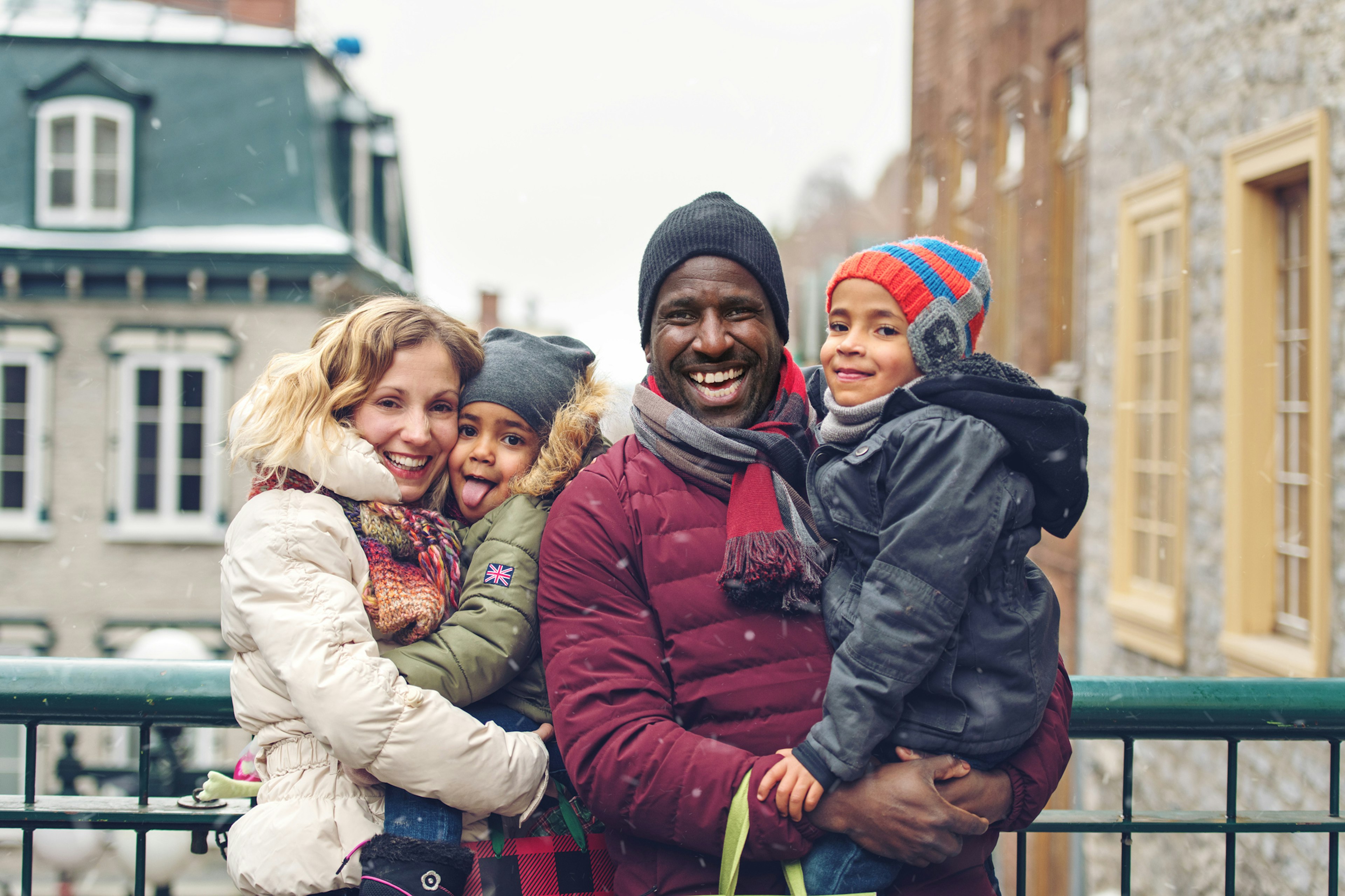 A family with two kids smiling in the snow in ϳé City