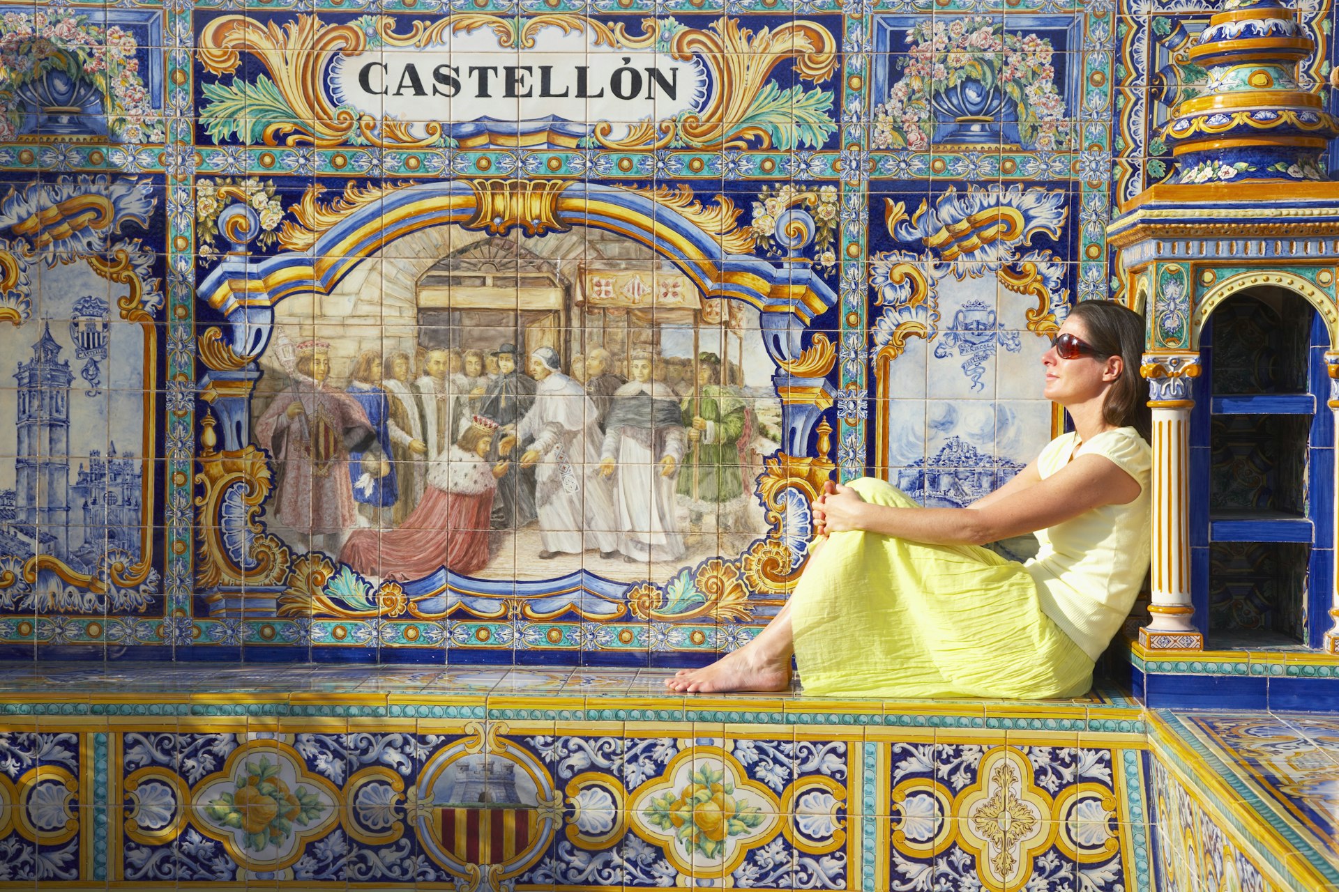 A woman sits on one of the ceramic benches at Plaza de Espana