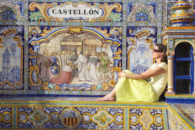 A woman sits on one of the ceramic benches at Plaza de Espana