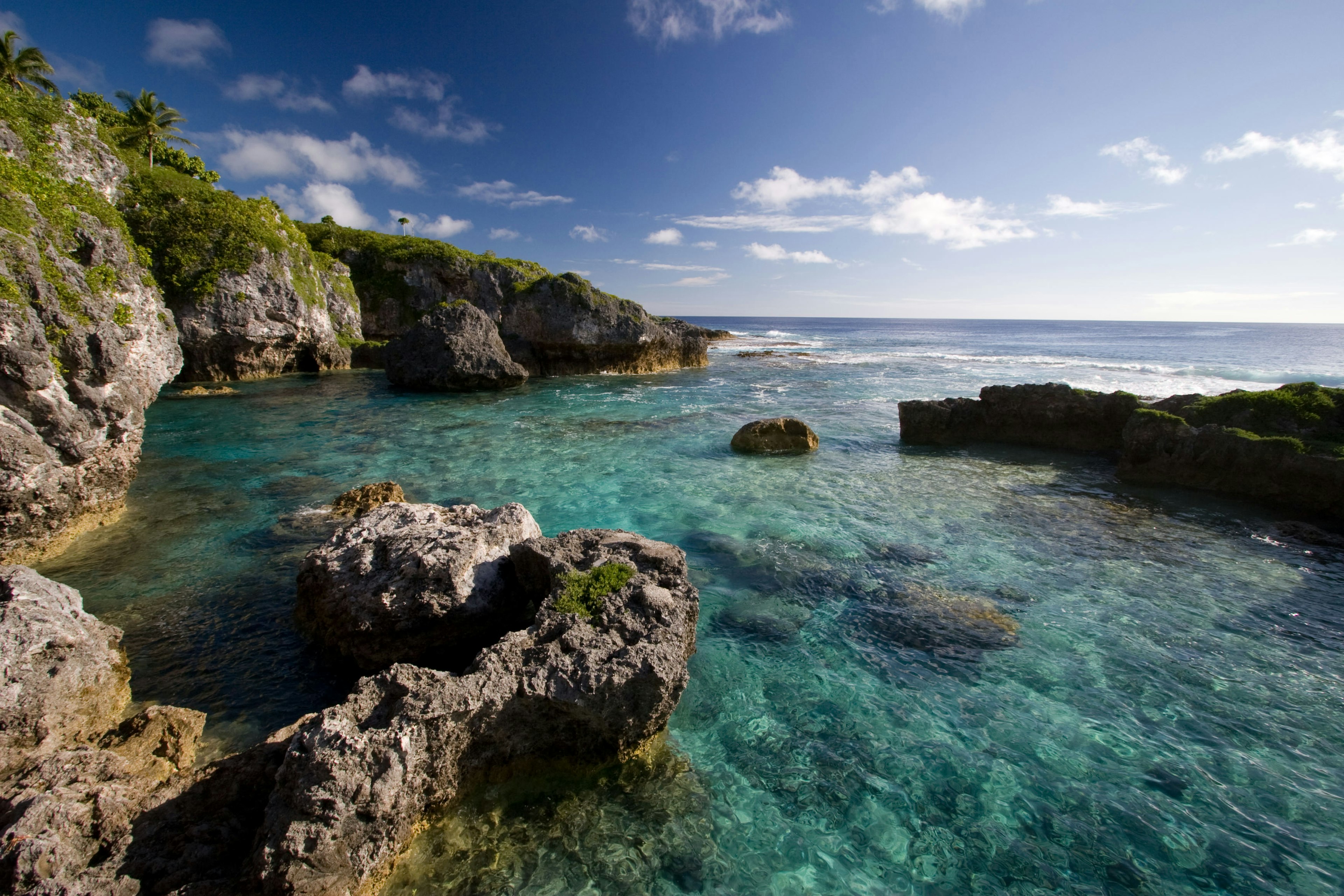 An empty natural pool with bright blue sea water right at the edge of the ocean