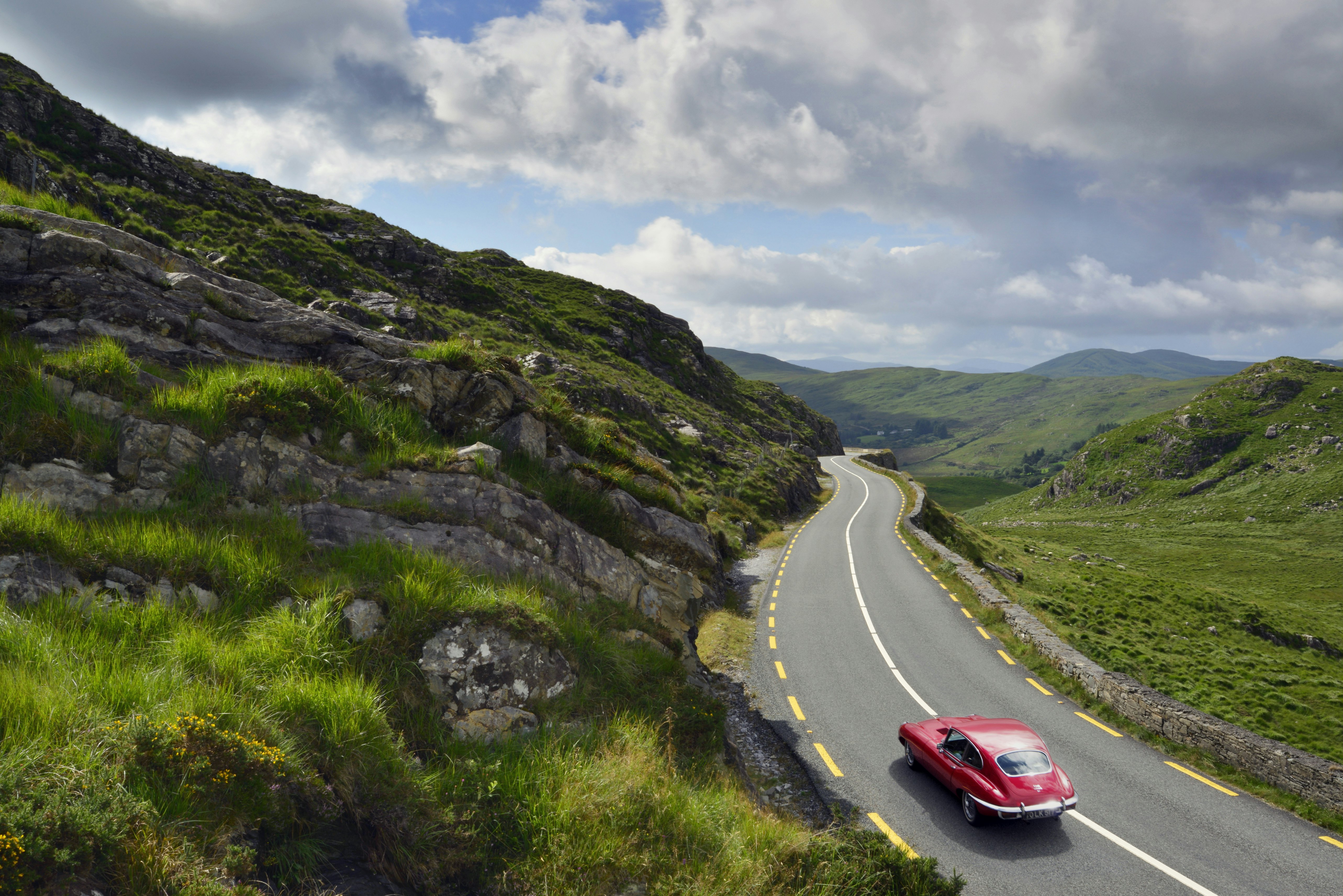 E-Type Jaguar driving on country road between Kenmare and Killarney, County Kerry, Ireland