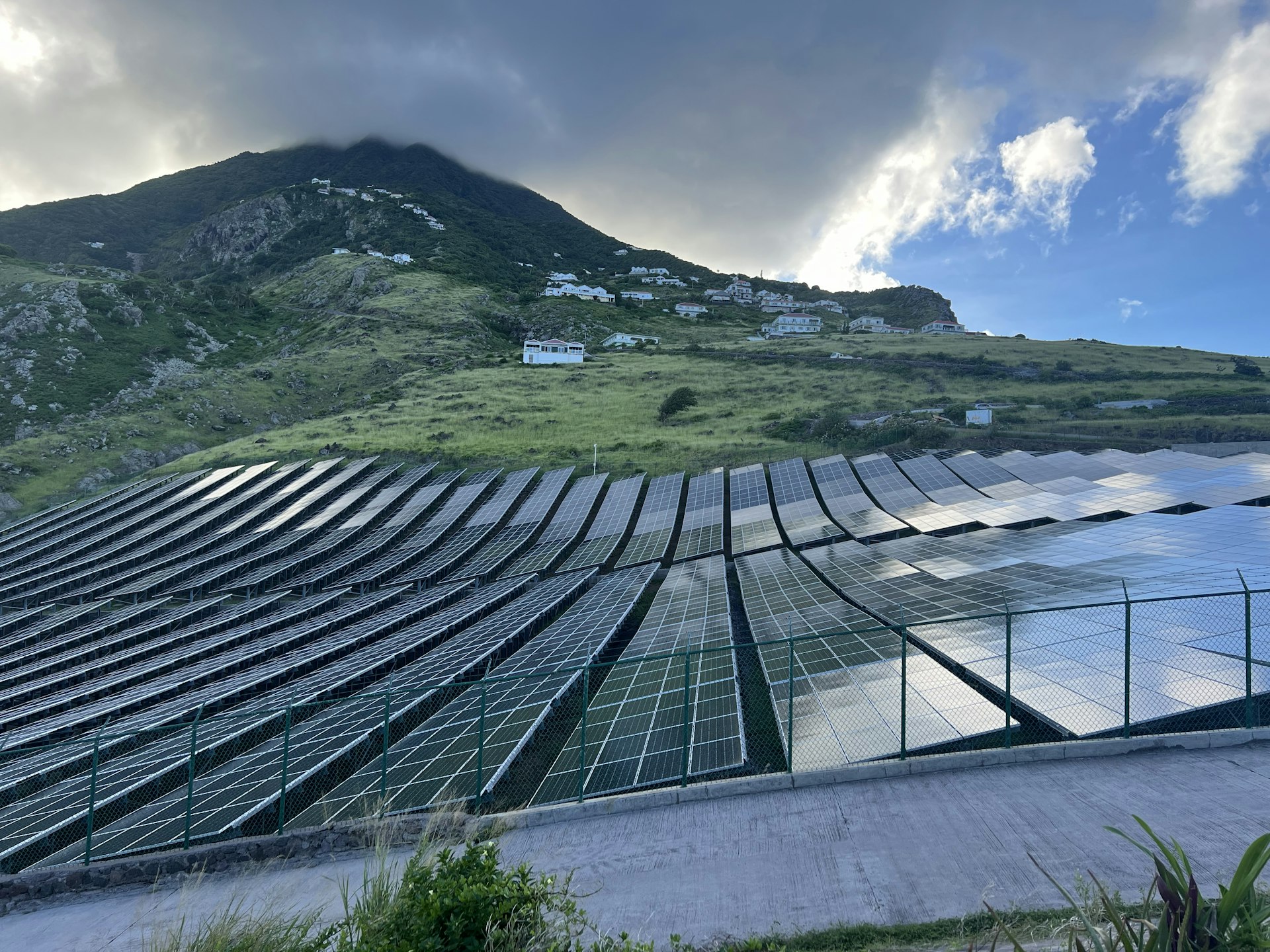 Rows of solar panels along the green mountains of the island of Saba