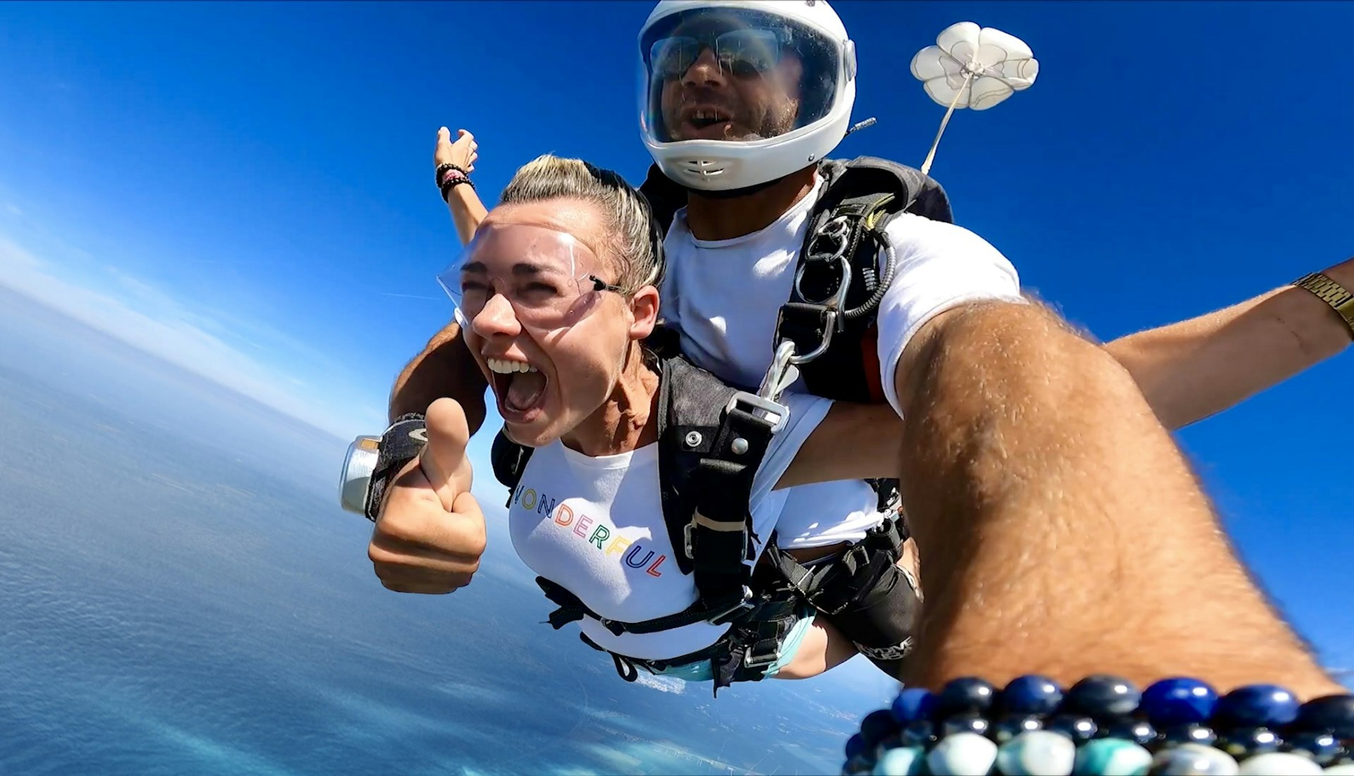 A woman gives the thumbs-up sign during a tandem skydive in the Maldives