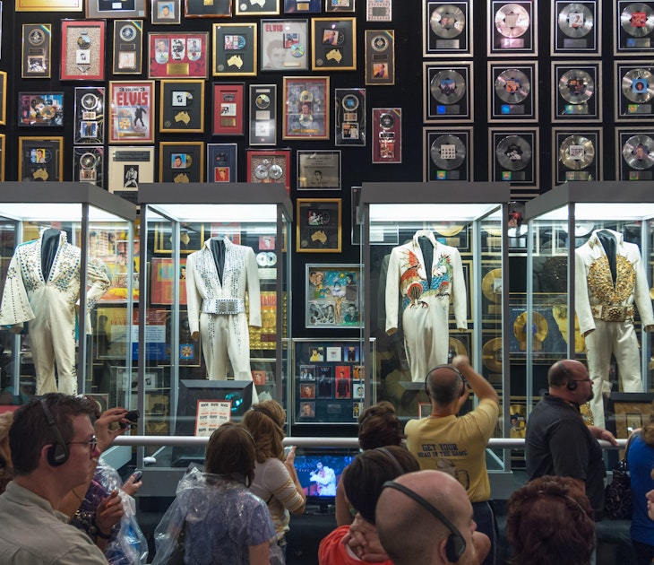 Elvis exhibit in the racquetball building, Graceland, Memphis, Tennessee.
521926910
Getty,  RFE,  nostalgia:CB2,  tourist:CB2,  sightseeing:CB2,  vacation:CB2,  landmark:CB2,  souvenir:CB2,  costume:CB2,  Americana:CB2,  indoors:CB2,  disc:CB2,  city:CB2,  tour:CB2,  Graceland:CB2,  elvis:CB2,  Elvis Presley:CB2,  building interior:CB2,  gold record:CB2,  incidental people:CB2,  jump suit:CB2,  platinum record:CB2,  travel & tourism:CB2,  Adult,  Coat,  Female,  Formal Wear,  Handbag,  Headphones,  Male,  Man,  Mobile Phone,  Pants,  Person,  Woman
