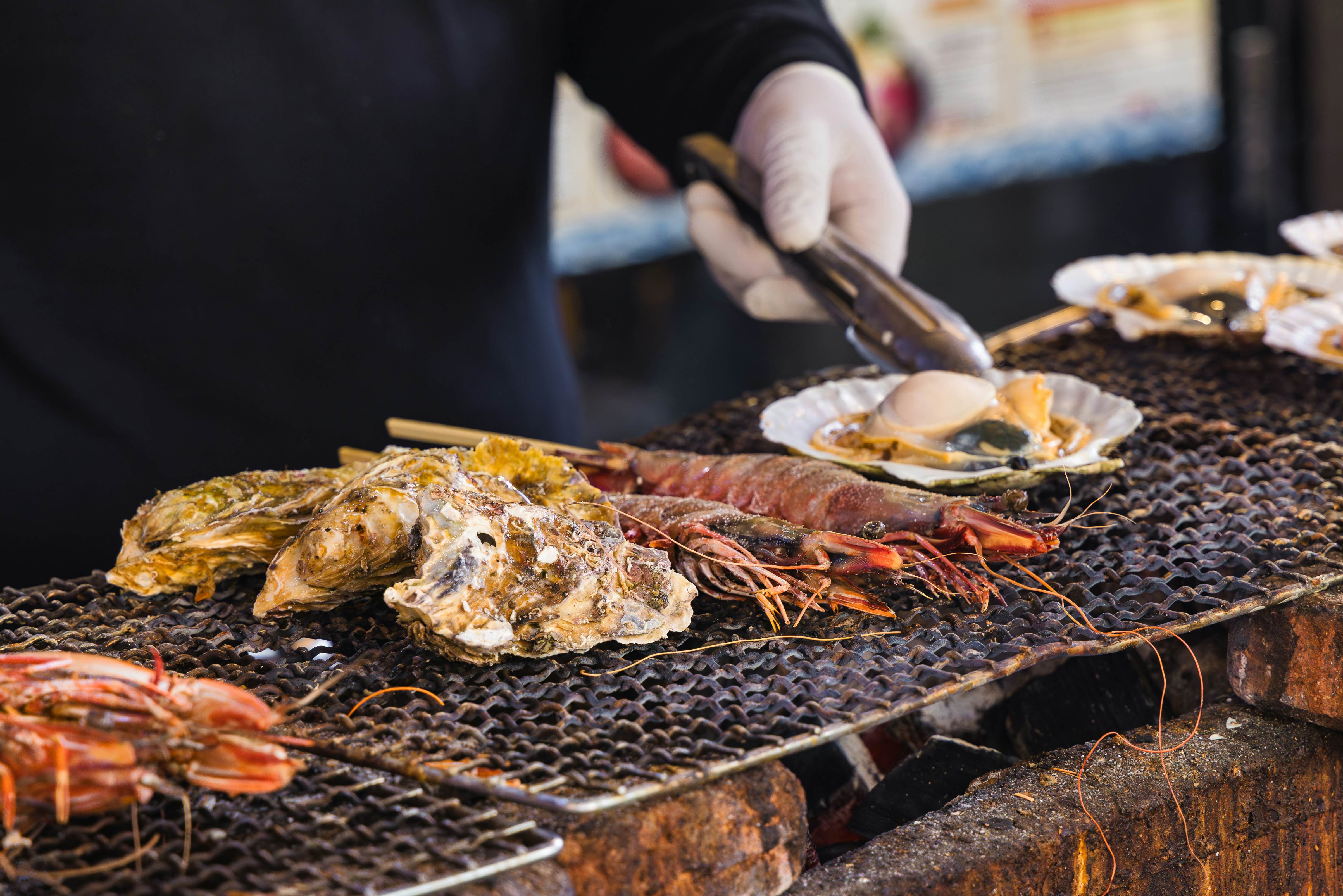 A chef at a street kitchen on the famous fish market Tsukiji in Tokyo, Japan, preparing seafood on a grill
1750853188