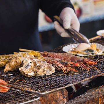 A chef at a street kitchen on the famous fish market Tsukiji in Tokyo, Japan, preparing seafood on a grill
1750853188