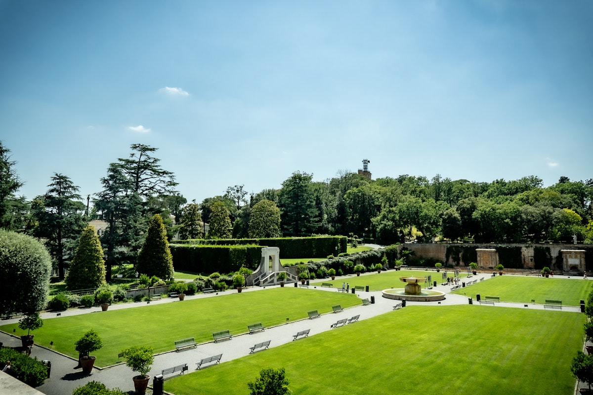 View of Vatican gardens on a sunny summer day. The square garden with green lawn, benches and trees