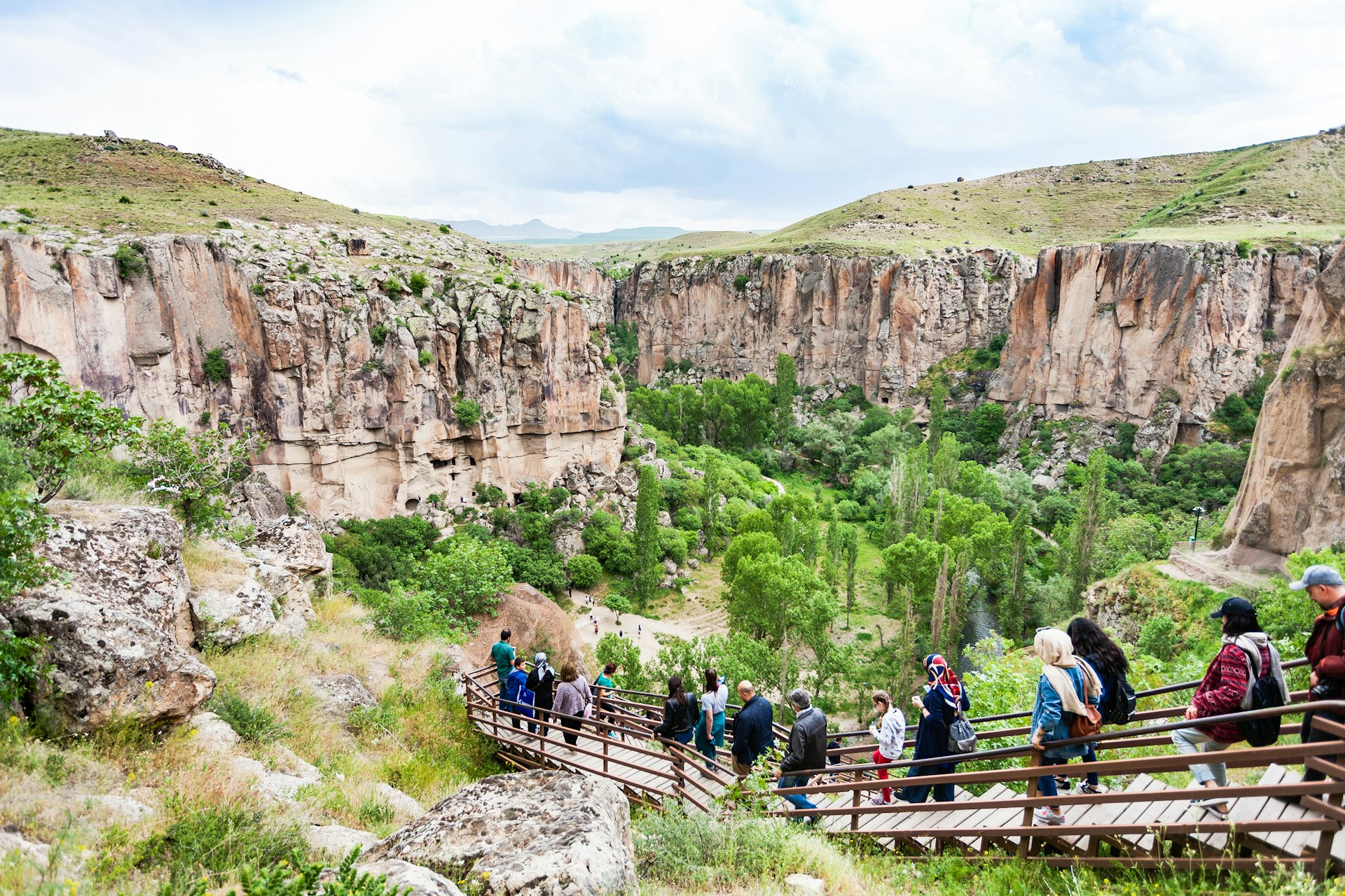 Tourists follow a boardwalk down into a valley