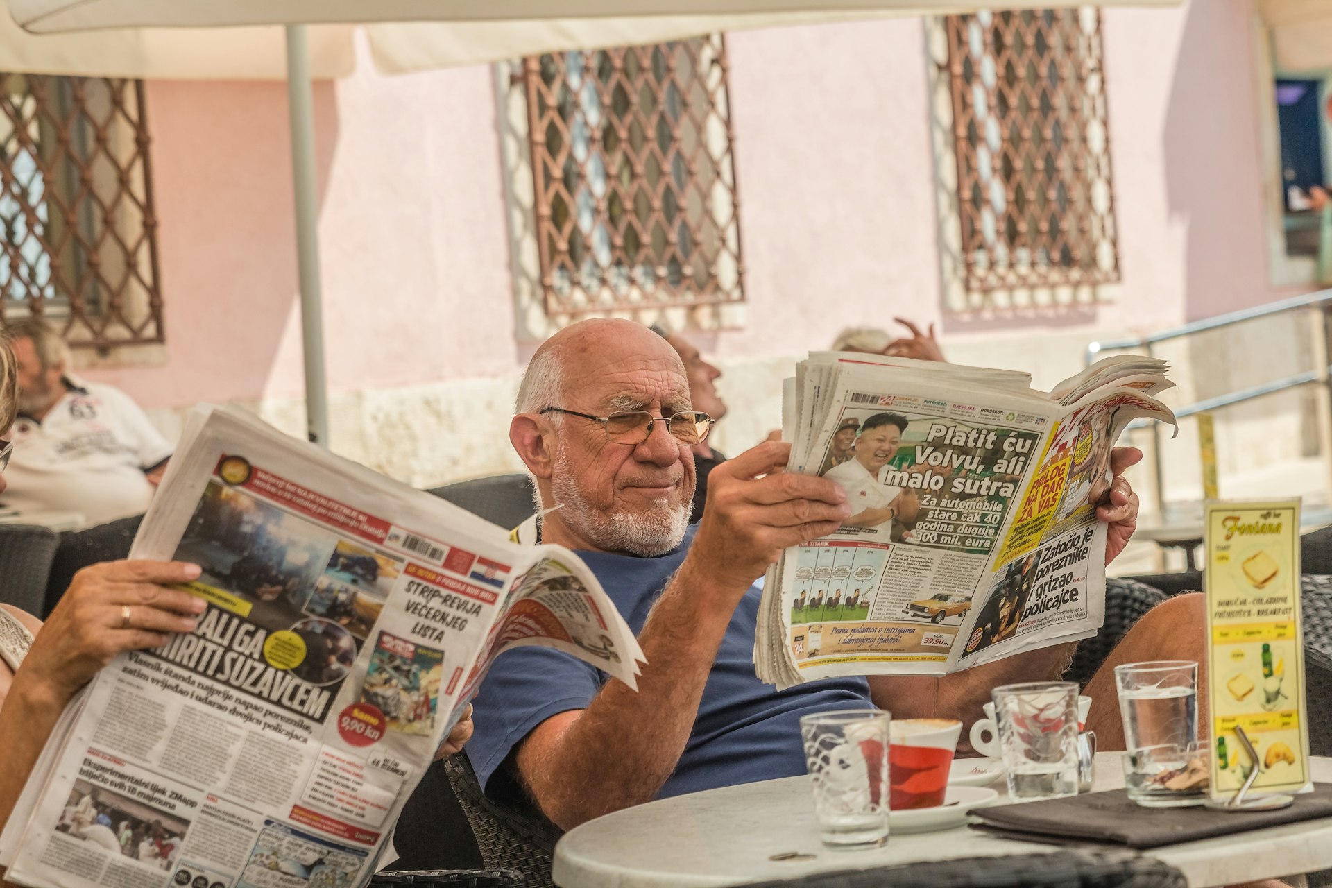 Men in a cafe read newspapers and drink coffee in the old town of Rovinj, Croatia