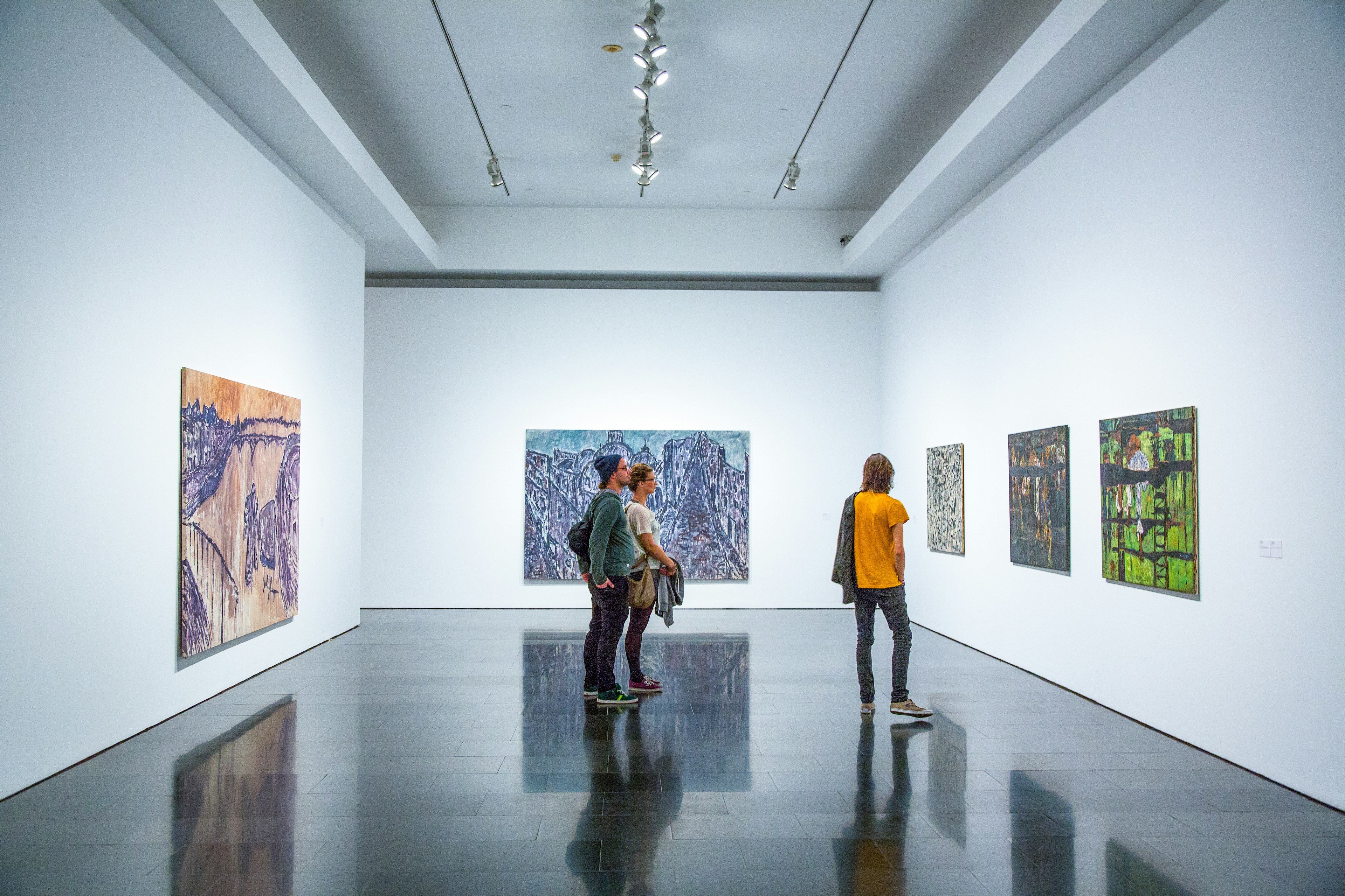 People stand in a white room admiring the artworks mounted on the walls