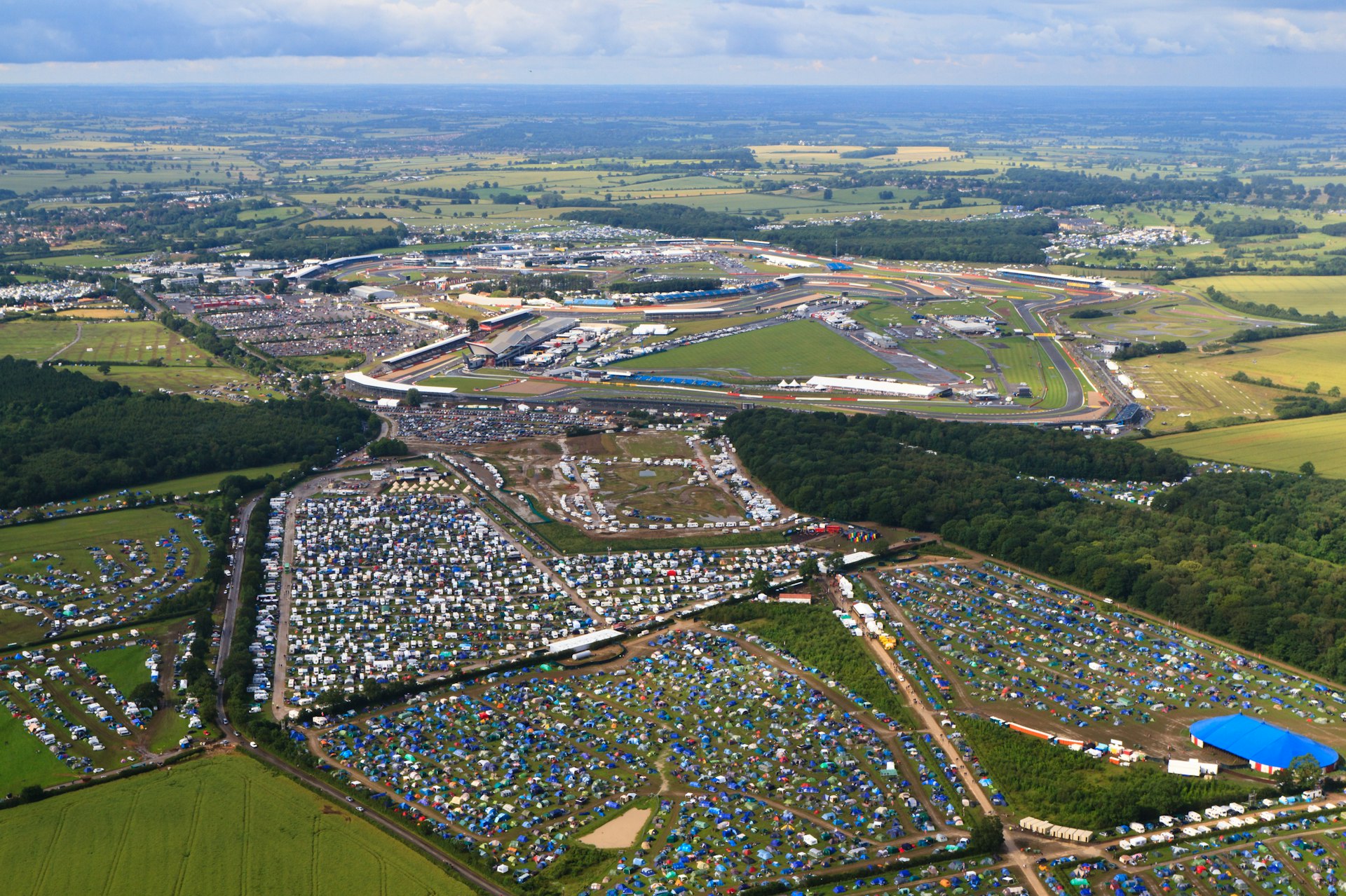 An aerial view of many tents in fields surrounding a race track