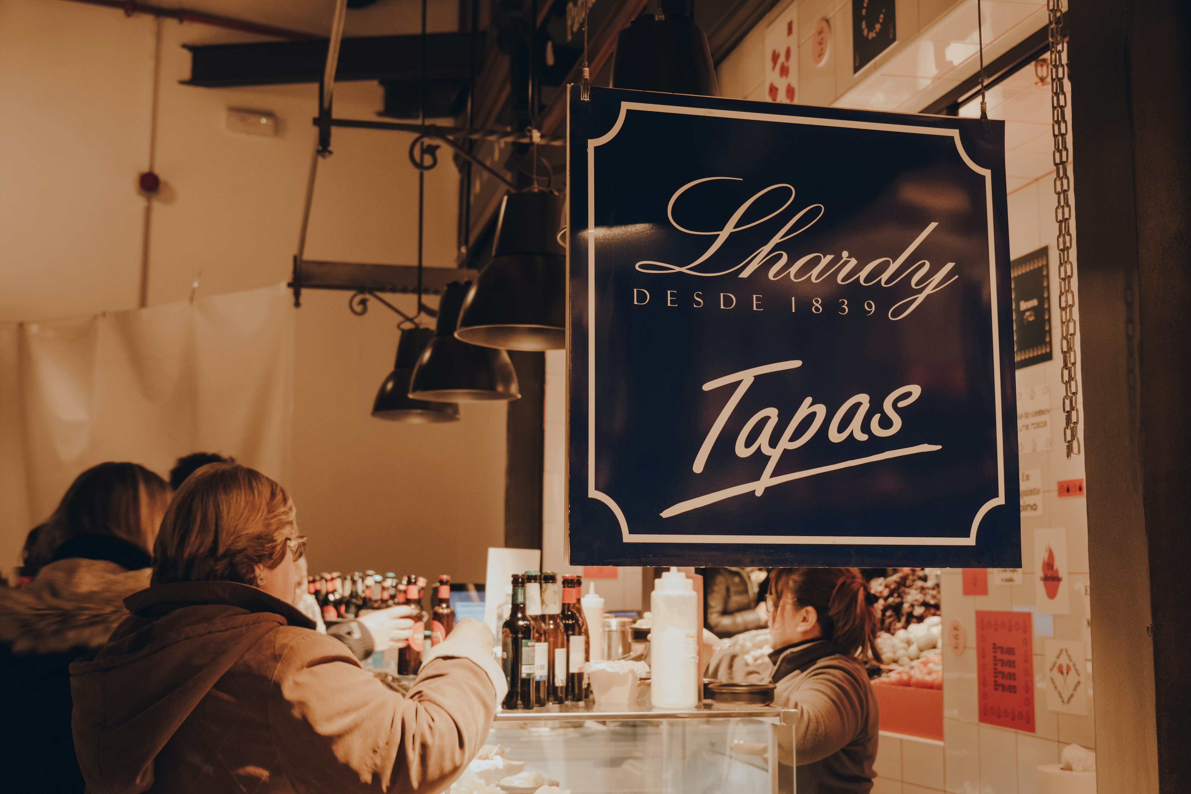 Sign at Lhardy Tapas stand inside Mercado de San Miguel ("Market of San Miguel"), a market in Madrid with stands serving variety of Spanish cuisine, selective focus