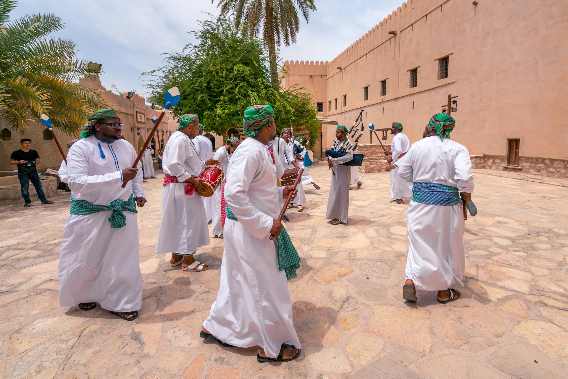 Men in traditional dress playing pipes, singing and dancing around in a ceremony, Nizwa, Oman