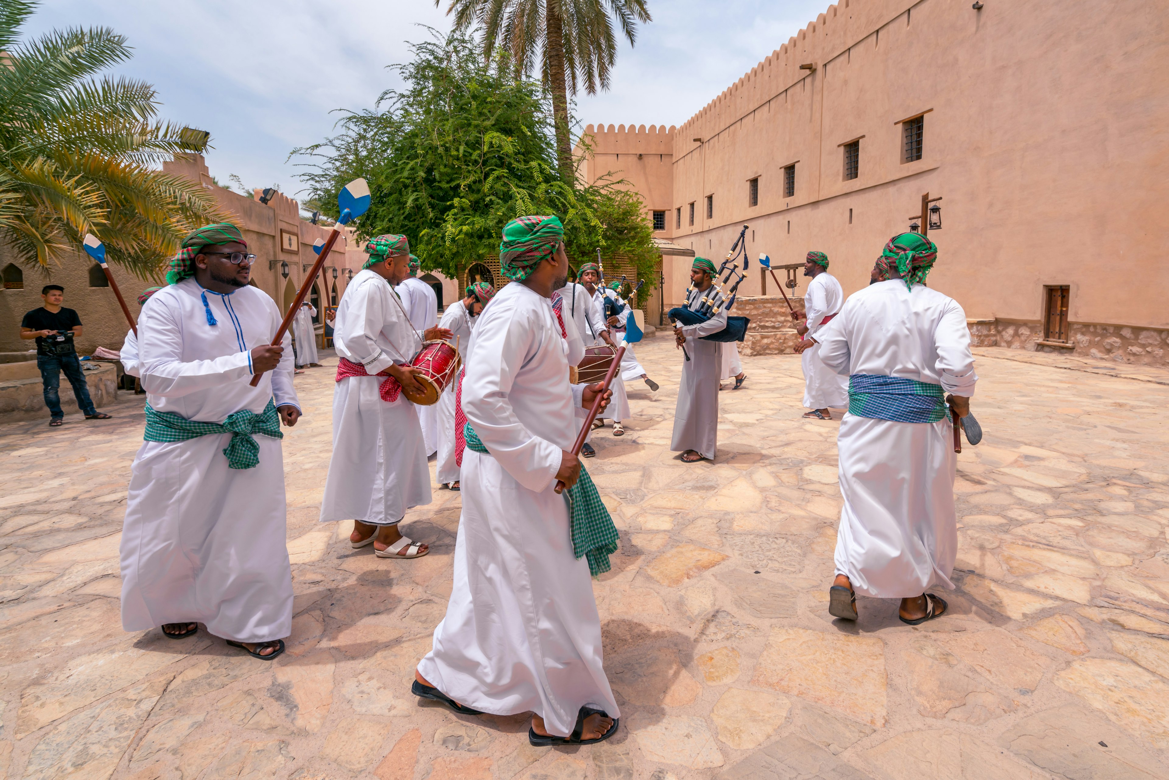 Men in traditional dress playing pipes, singing and dancing around in a ceremony, Nizwa, Oman