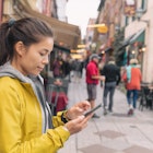 Woman using mobile phone app while walking down the street in Québec City, Canada