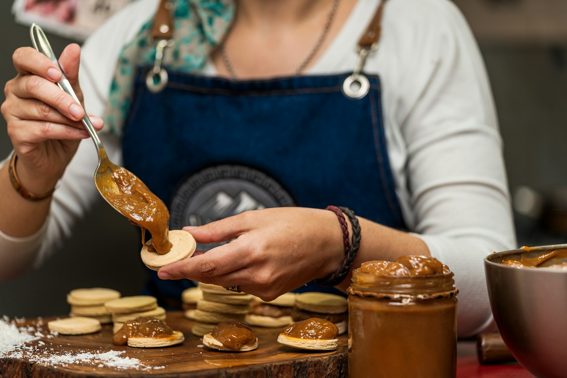 A woman combines dulce de leche with dough discs to make alfajores, Argentina