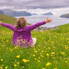 A happy tourist sits in a meadow and admires the view of the Faroe Islands, Kingdom of Denmark. Europe.; Shutterstock ID 2065411541; GL: 65050; netsuite: Online Editorial; full: Faroe Islands articles; name: Tasmin Waby
2065411541