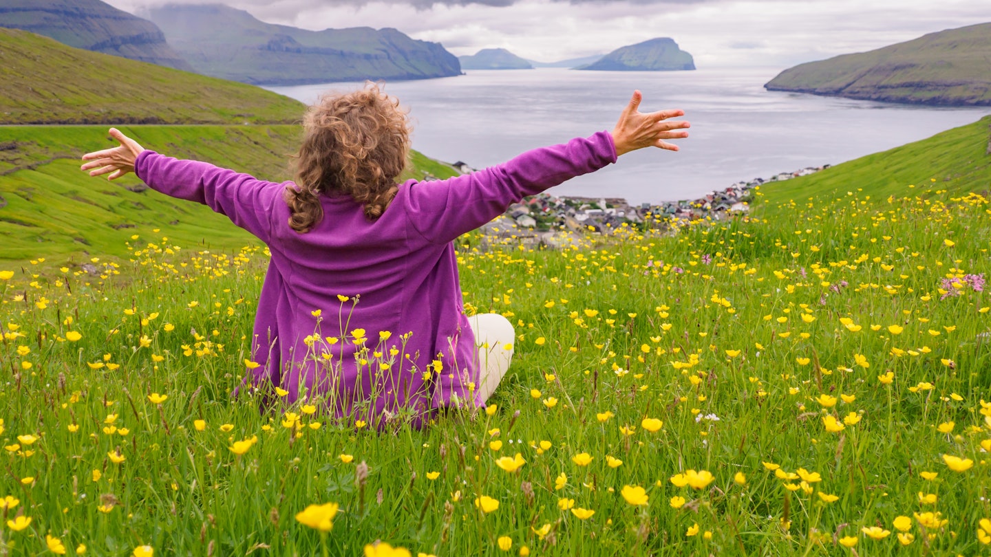 A happy tourist sits in a meadow and admires the view of the Faroe Islands, Kingdom of Denmark. Europe.; Shutterstock ID 2065411541; GL: 65050; netsuite: Online Editorial; full: Faroe Islands articles; name: Tasmin Waby
2065411541
