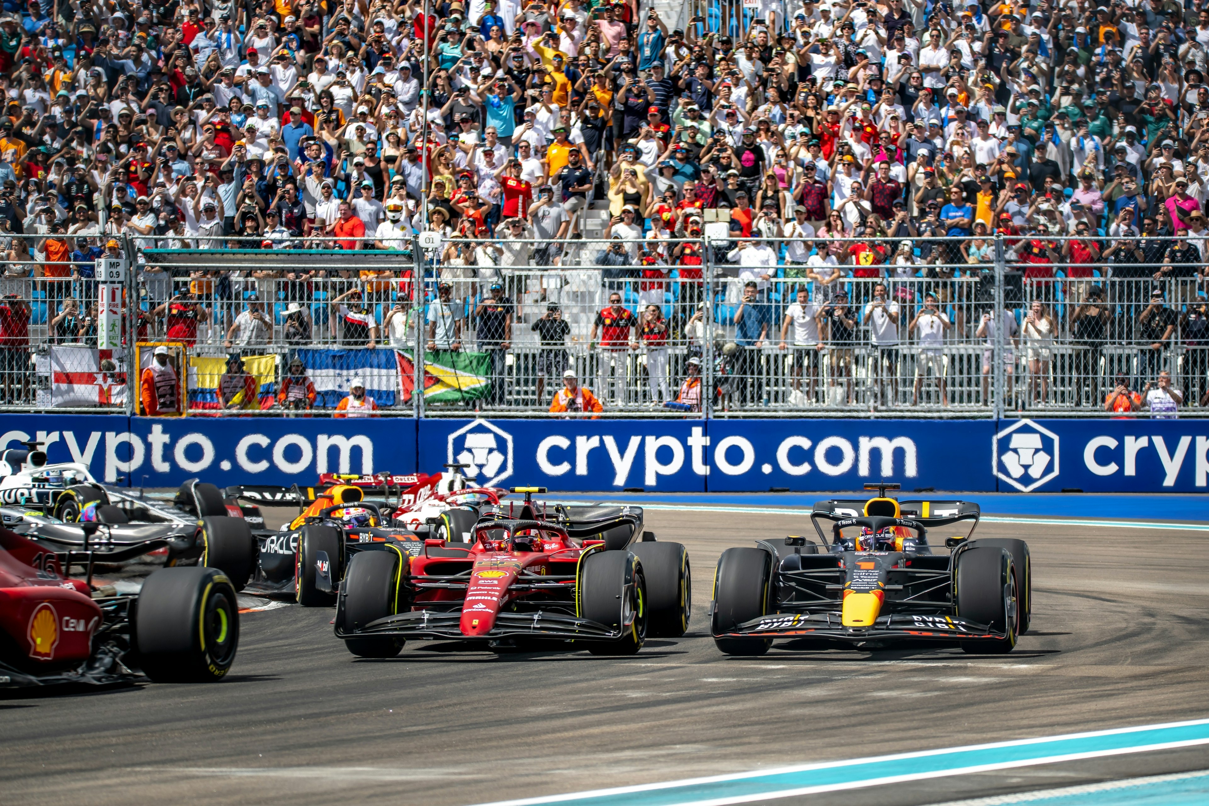 Cars on a racetrack with crowds of people watching from grandstand seats