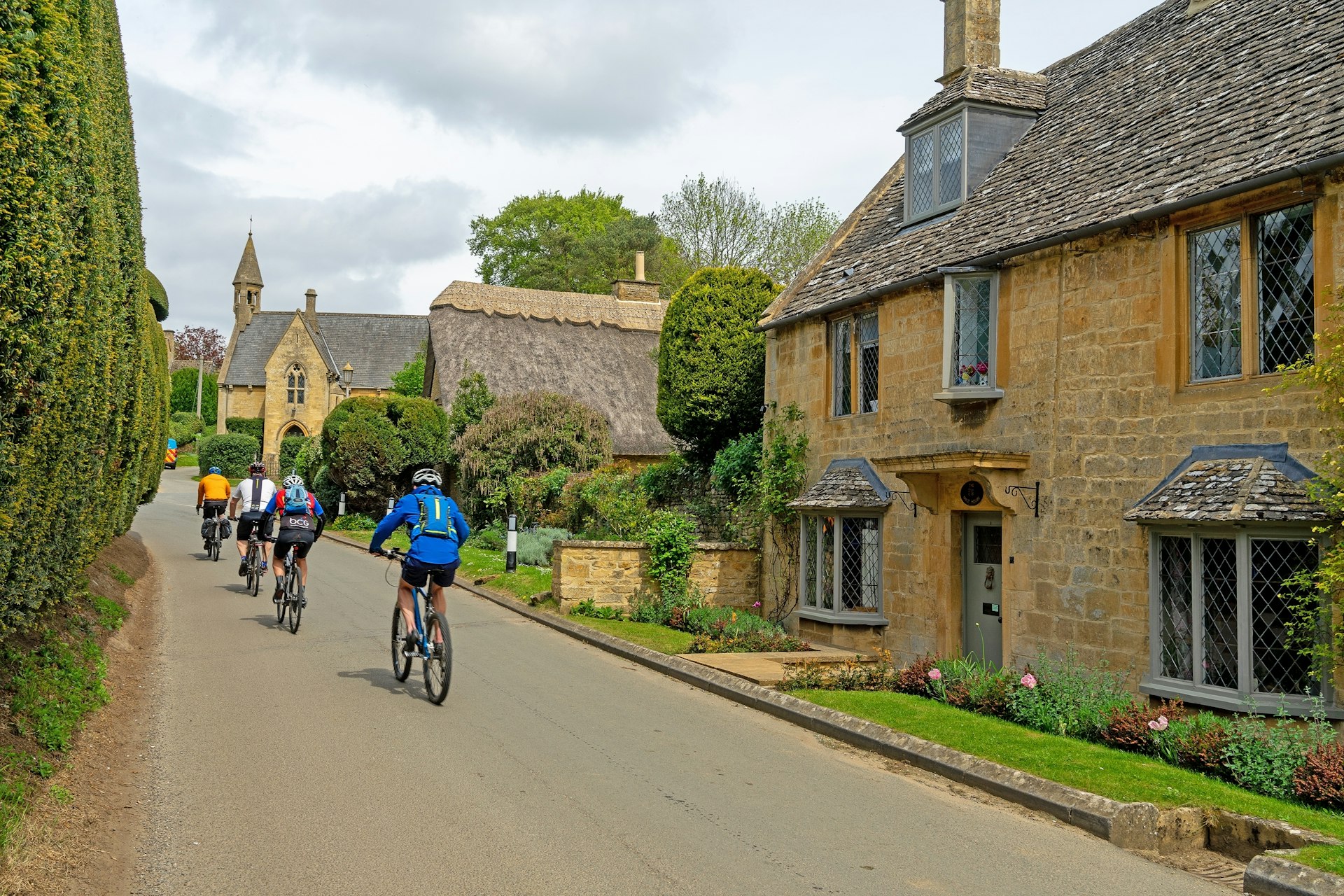 Four cyclists peddle through a village