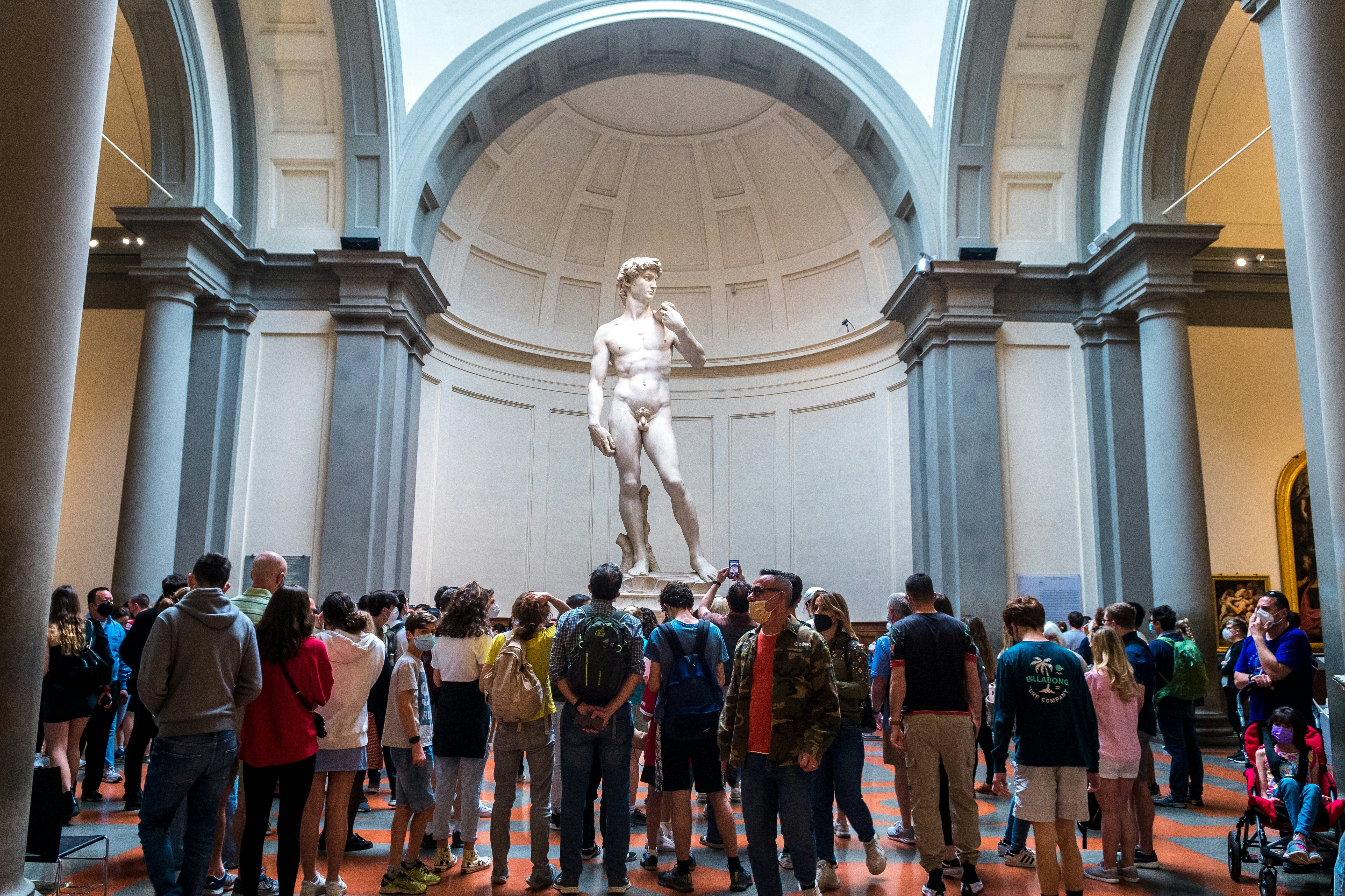 Crowded gallery by tourists trying to take photo to david sculpture in accademia.