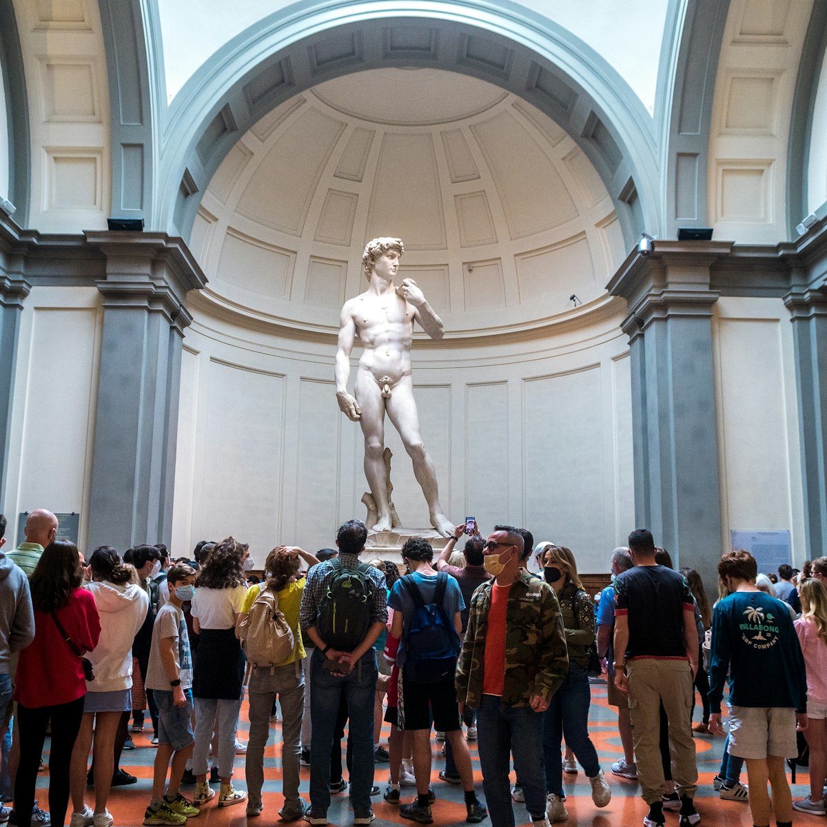 Crowded gallery by tourists trying to take photo to david sculpture in accademia.