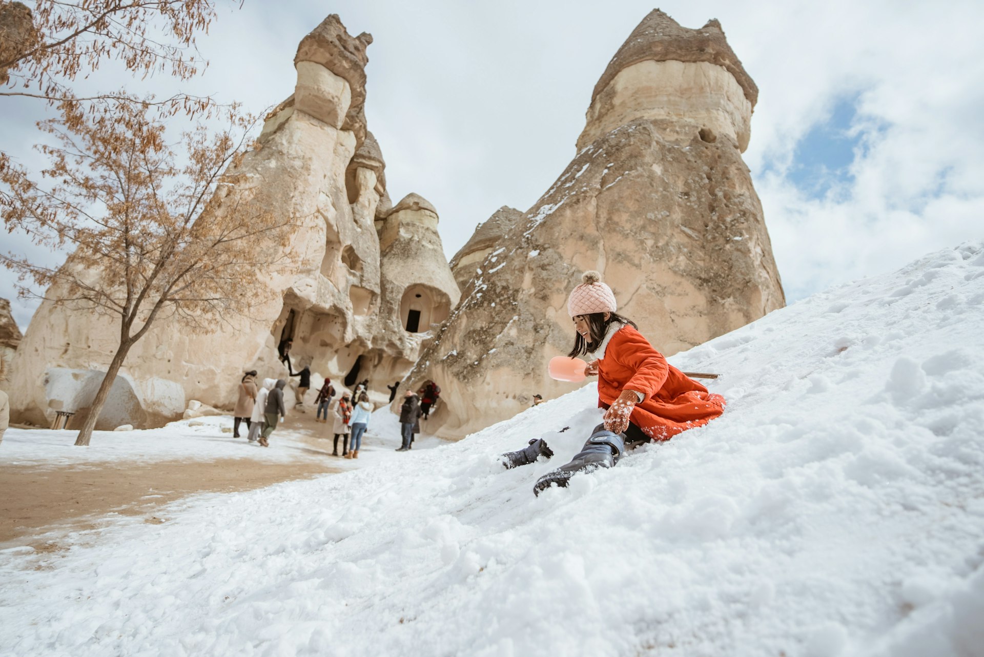 A little girl slides down the snow on the fairy chimneys in Cappadocia. 