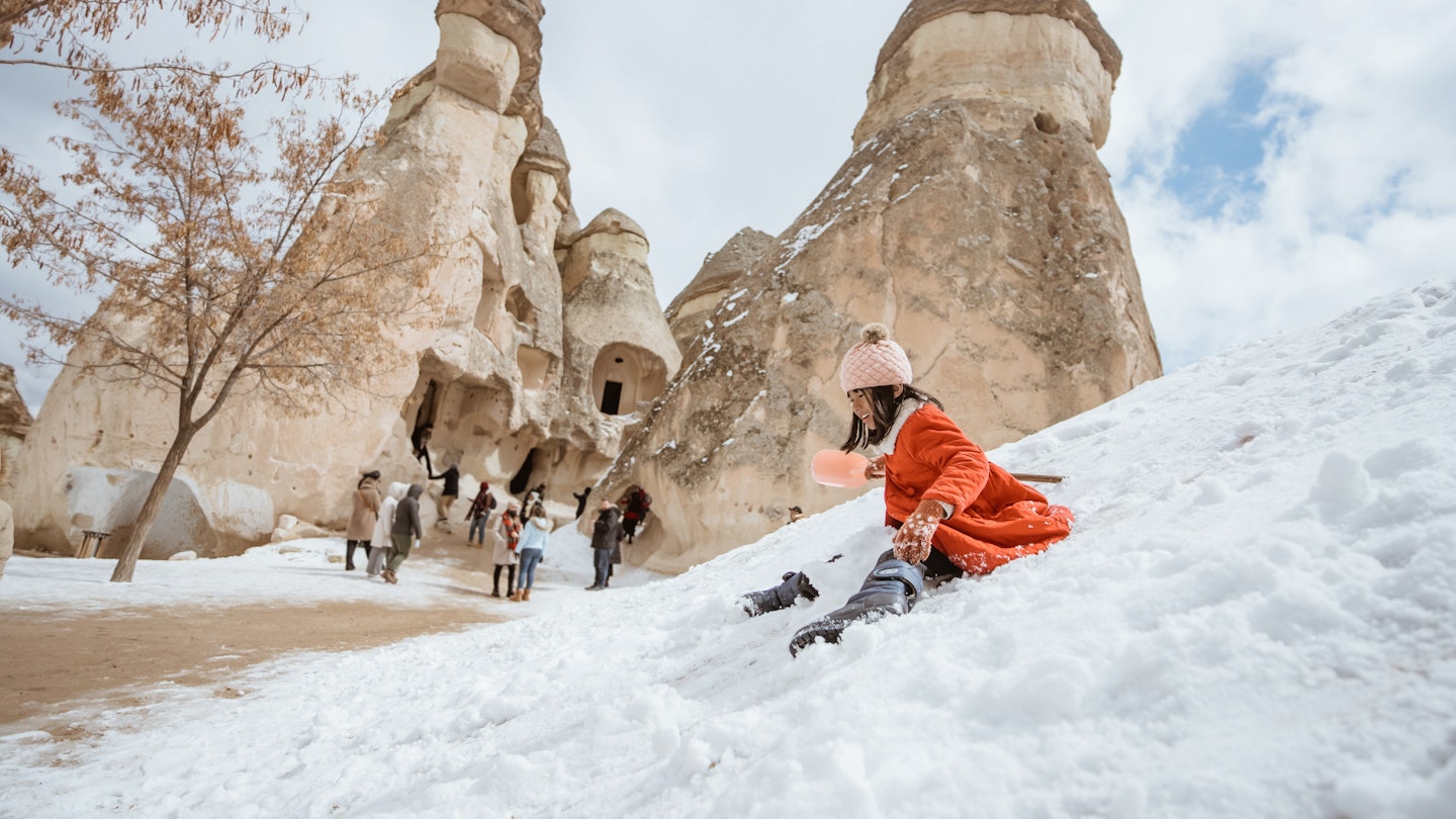happy little girl in red sliding on a pile of snow in pasabag valley cappadocia; Shutterstock ID 2188765535; GL: 65050 ; netsuite: Online Editorial; full: Cappadocia articles; name: Tasmin Waby
2188765535