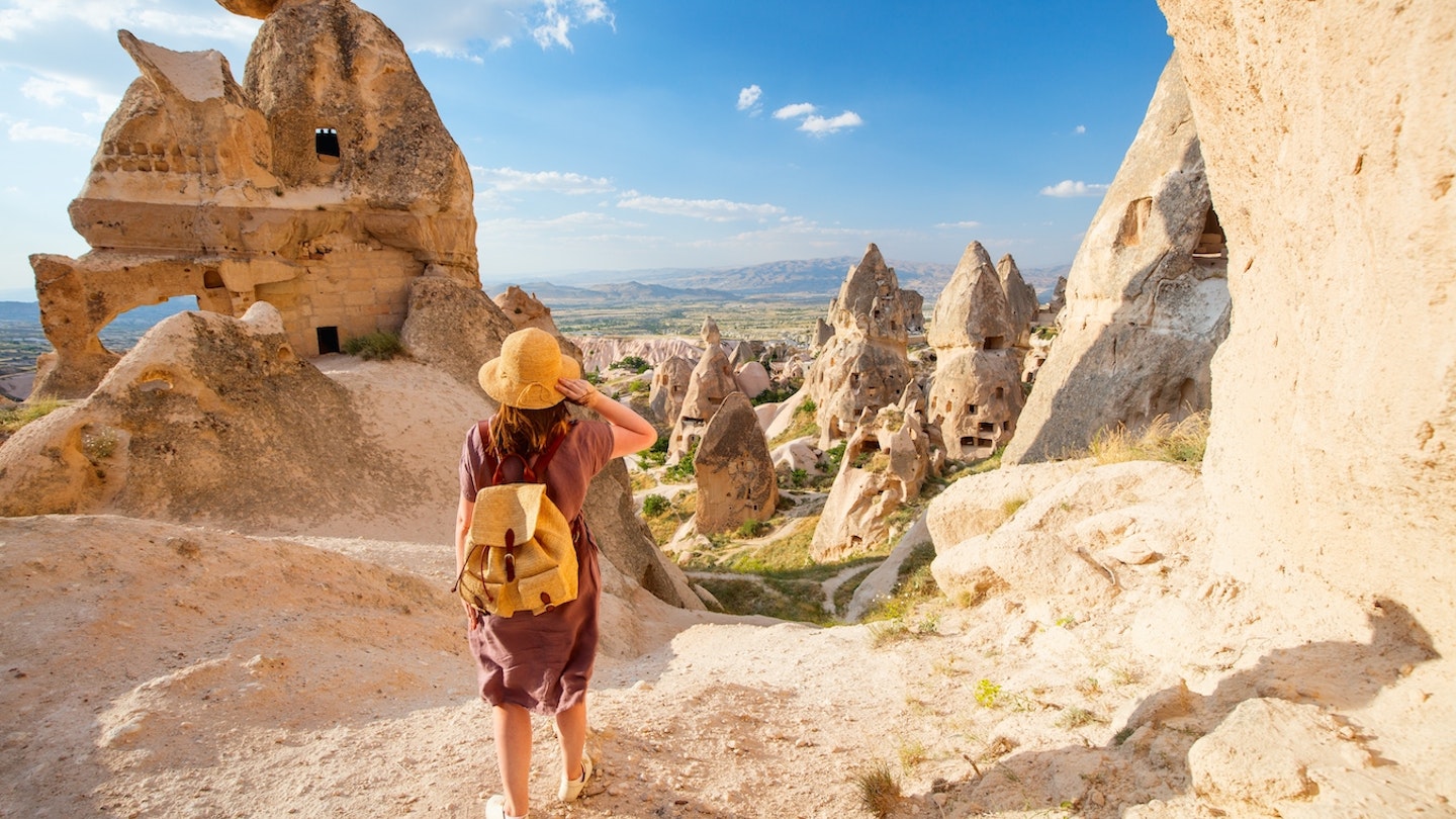 A young woman exploring a valley with rock formations and fairy chimneys near Uchisar castle in Cappadocia Turkey