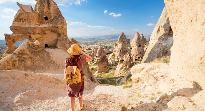 A young woman exploring a valley with rock formations and fairy chimneys near Uchisar castle in Cappadocia Turkey