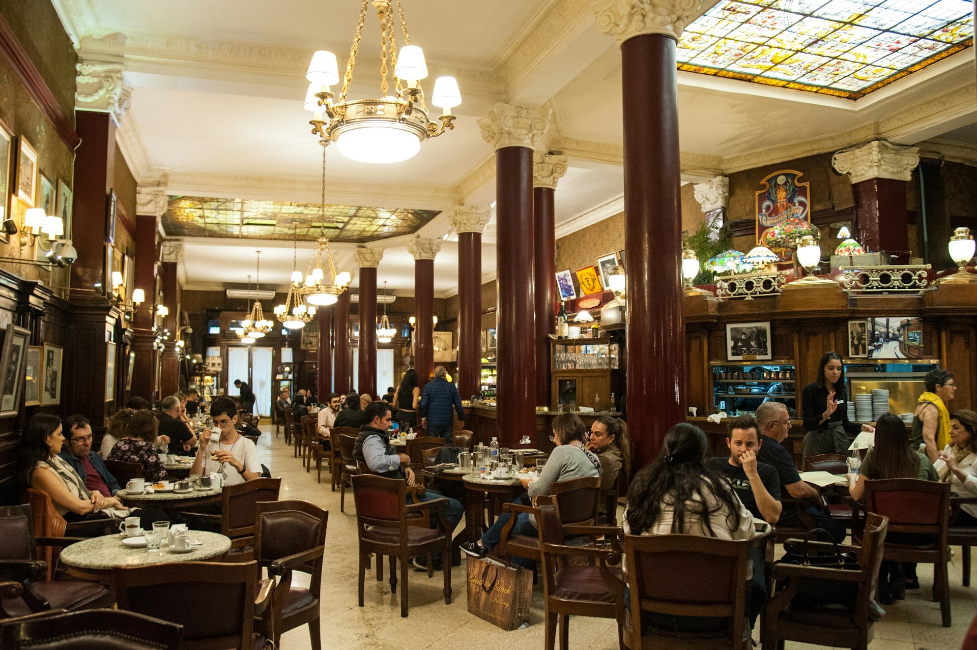 People sit at tables in the ornate interior of Cafe Tortoni, Buenos Aires, Argentina