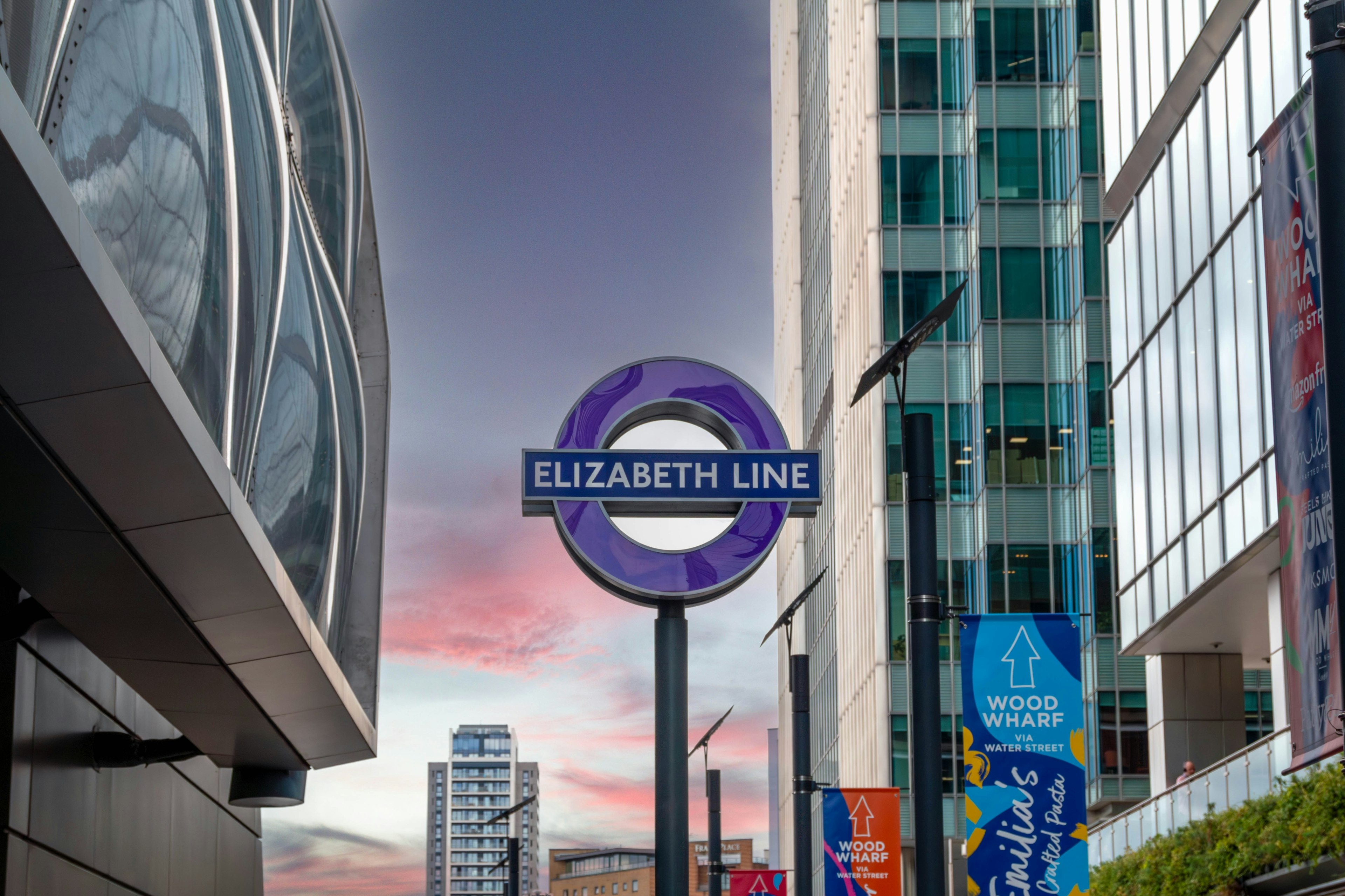 Railway sign for the Elizabeth Line at Canary Wharf in London just before sunset