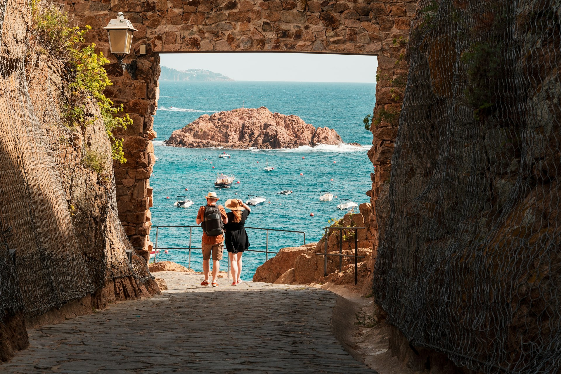 A couple at the gate to the Villa Vella fortress, looking out to the Mediterranean Sea, Tossa de Mar, Catalonia, Spain