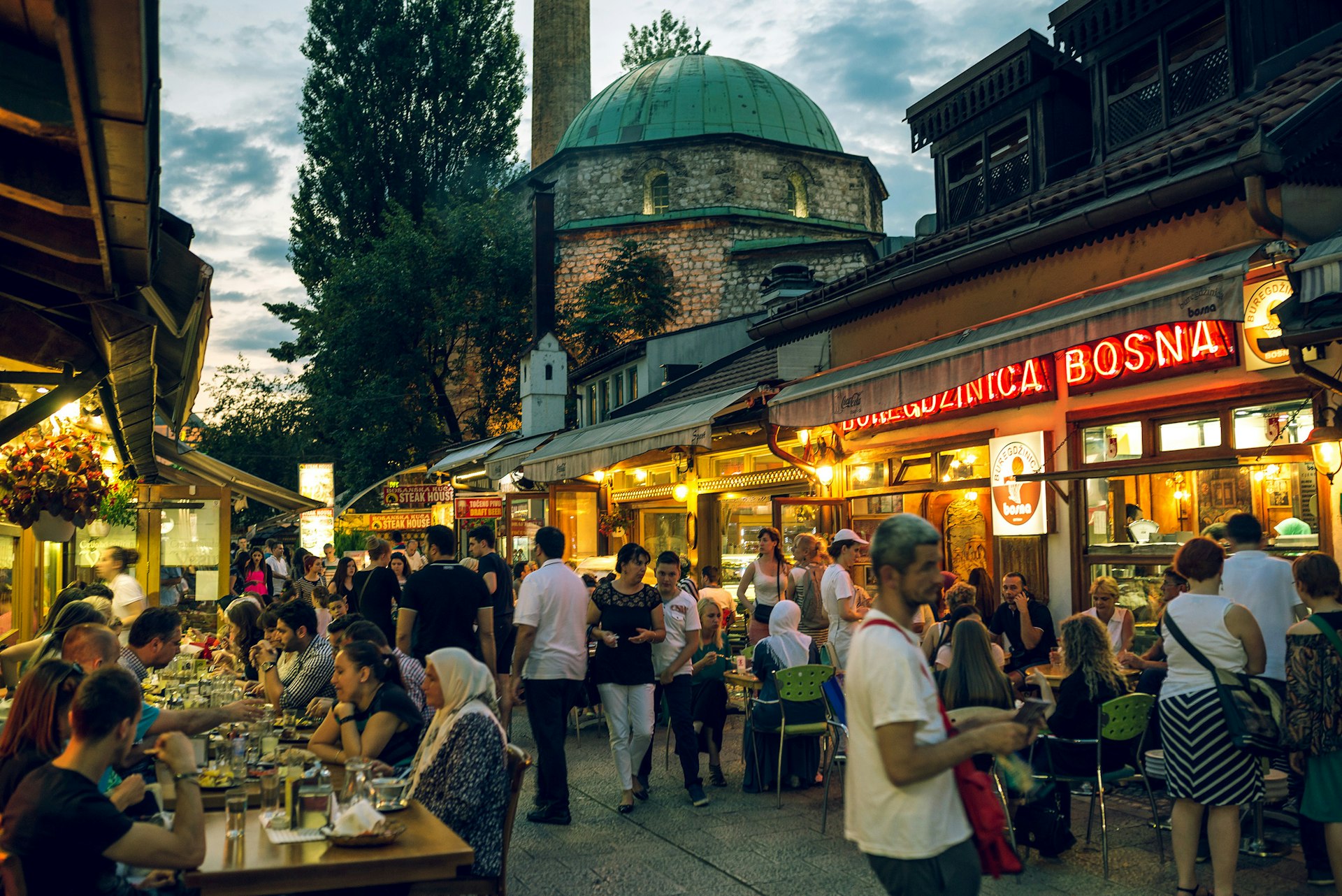 People gather at tables outside restaurants for a meal as the sun sets during Ramadan