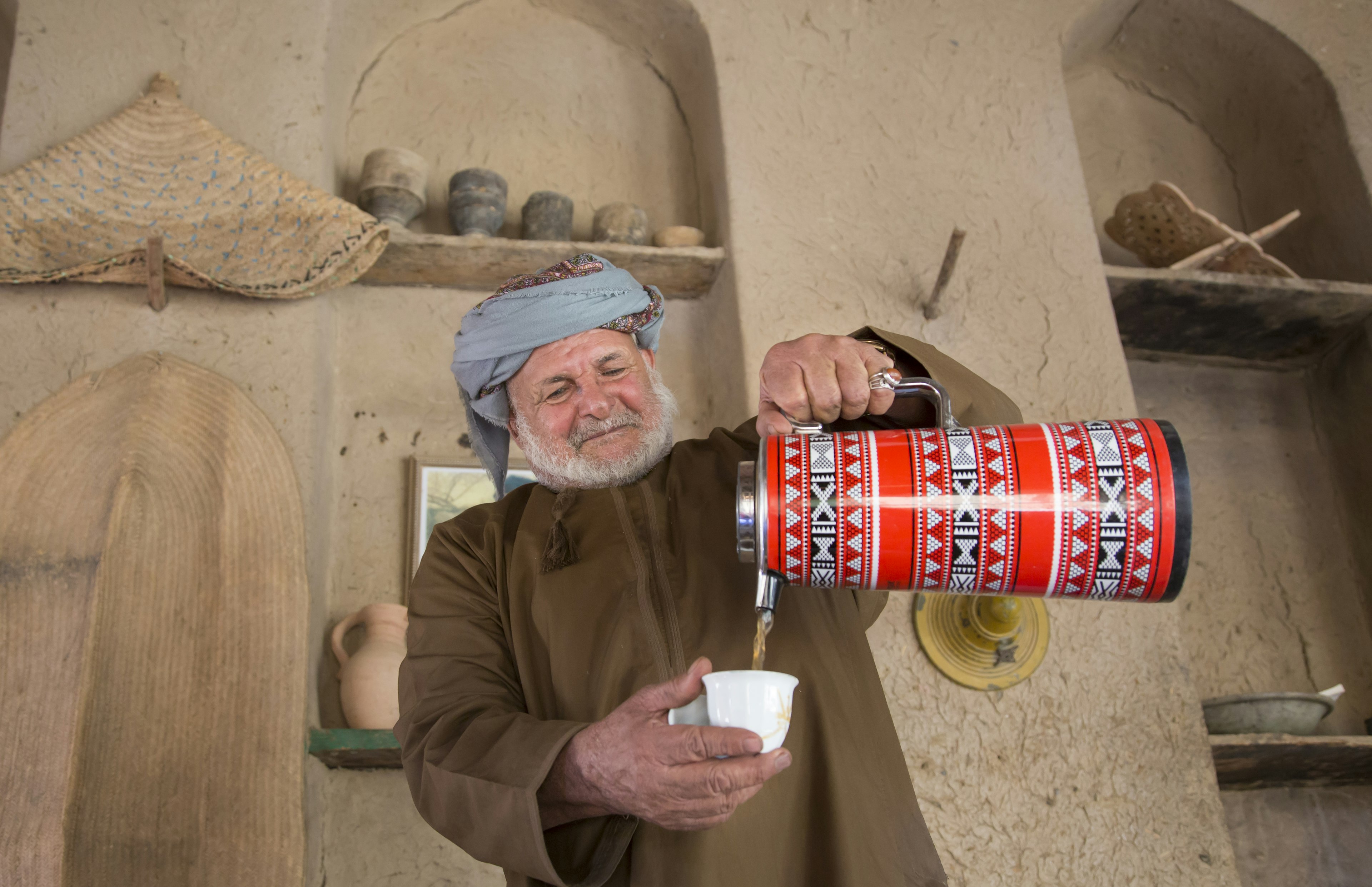 A man serves qahwa, traditional coffee, from a thermos in Oman