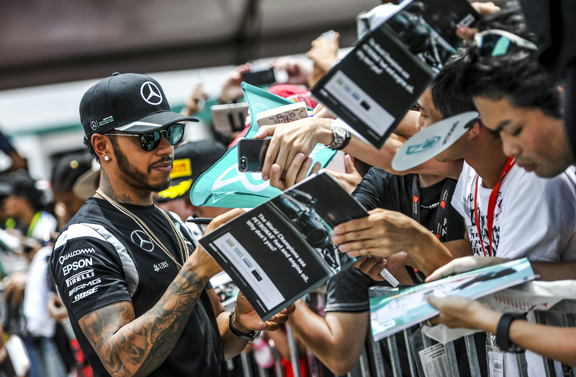 A racing-car driver signs programs held out by fans in a crowd